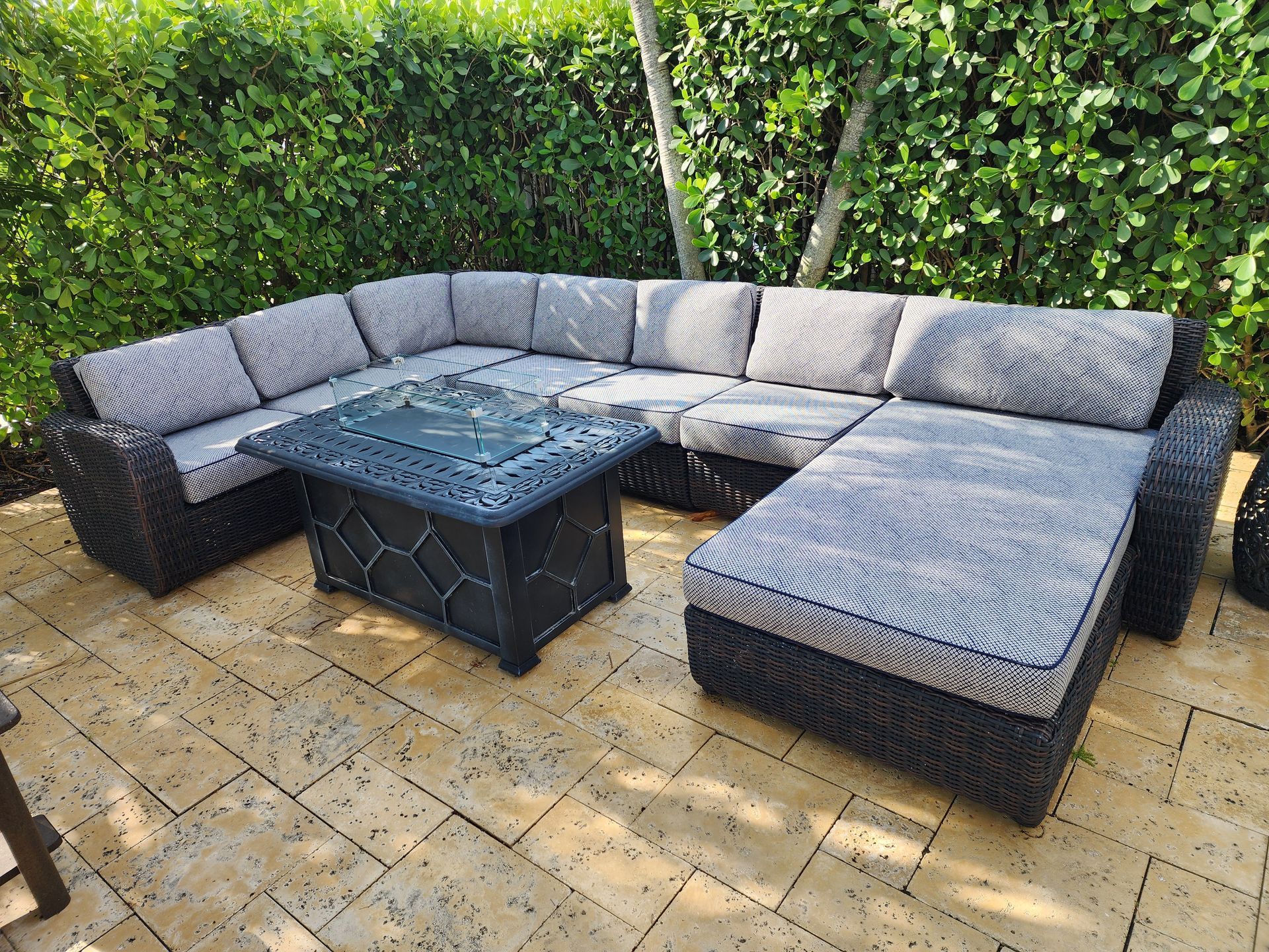 Outdoor sectional sofa with a fire pit table, grey cushions, dark brown wicker, on a patio.
