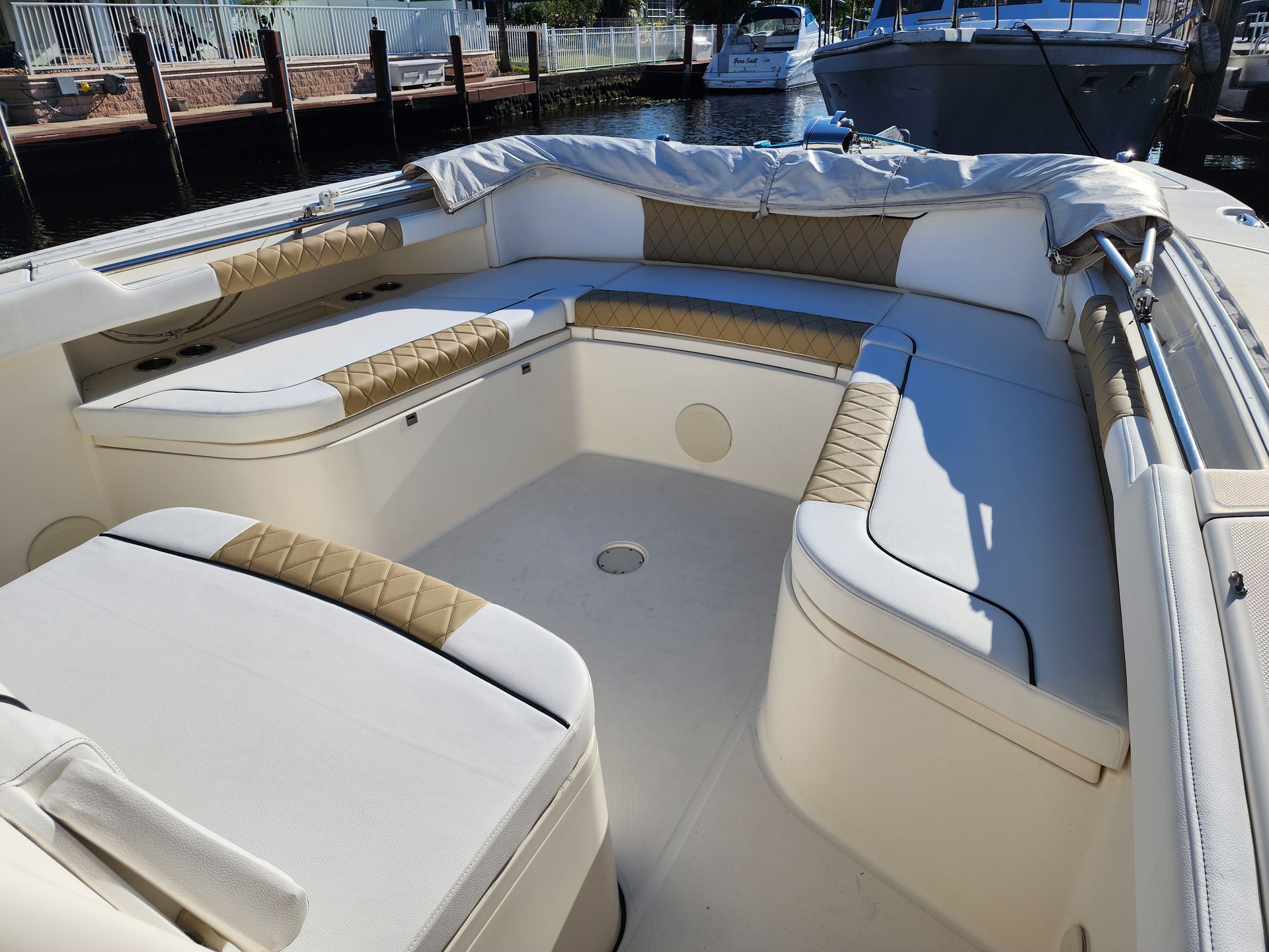 Boat interior with white and tan upholstery and a U-shaped seating area.