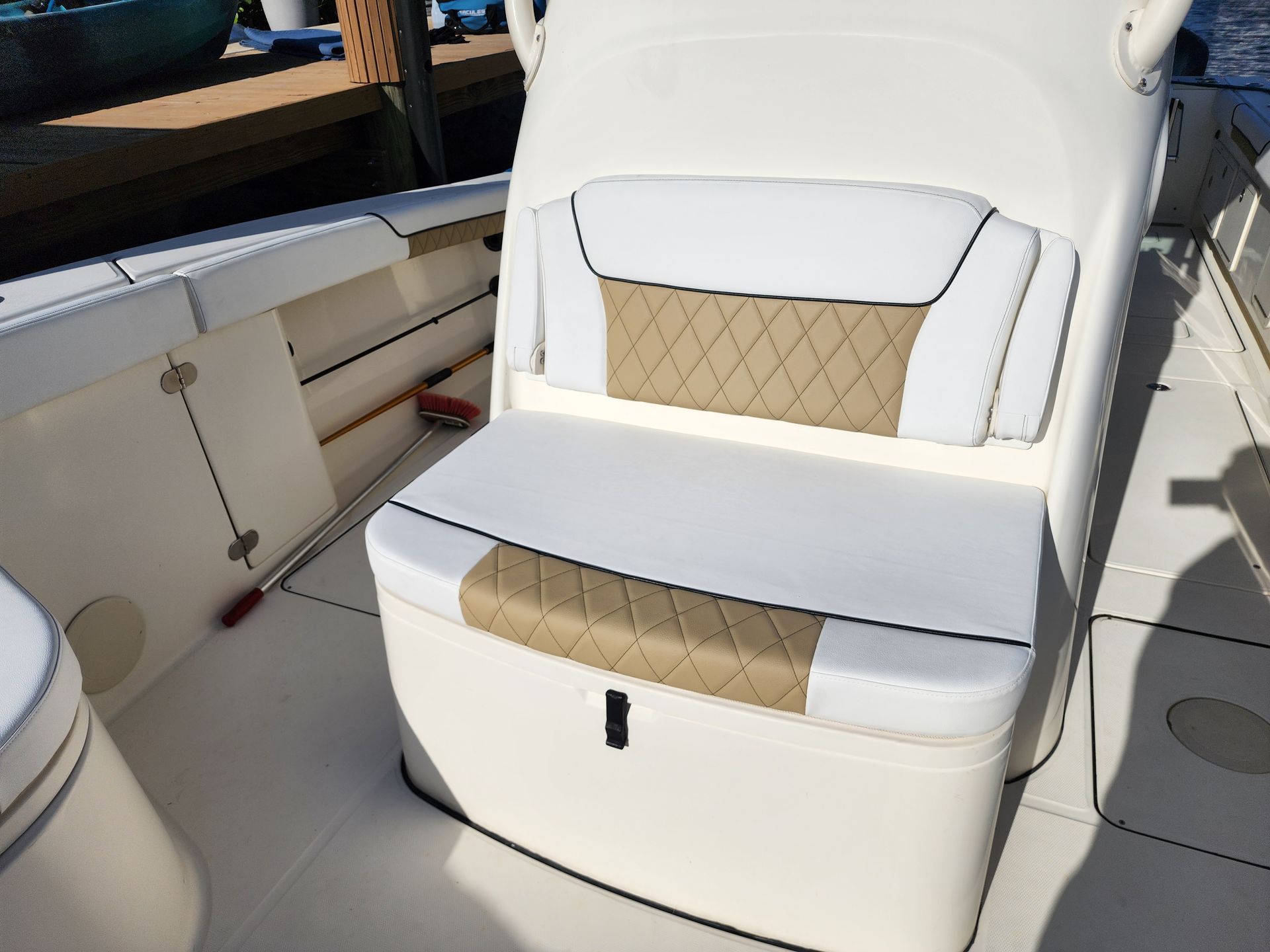 Boat seat with white and tan upholstery, diamond stitching, on a sunny deck.