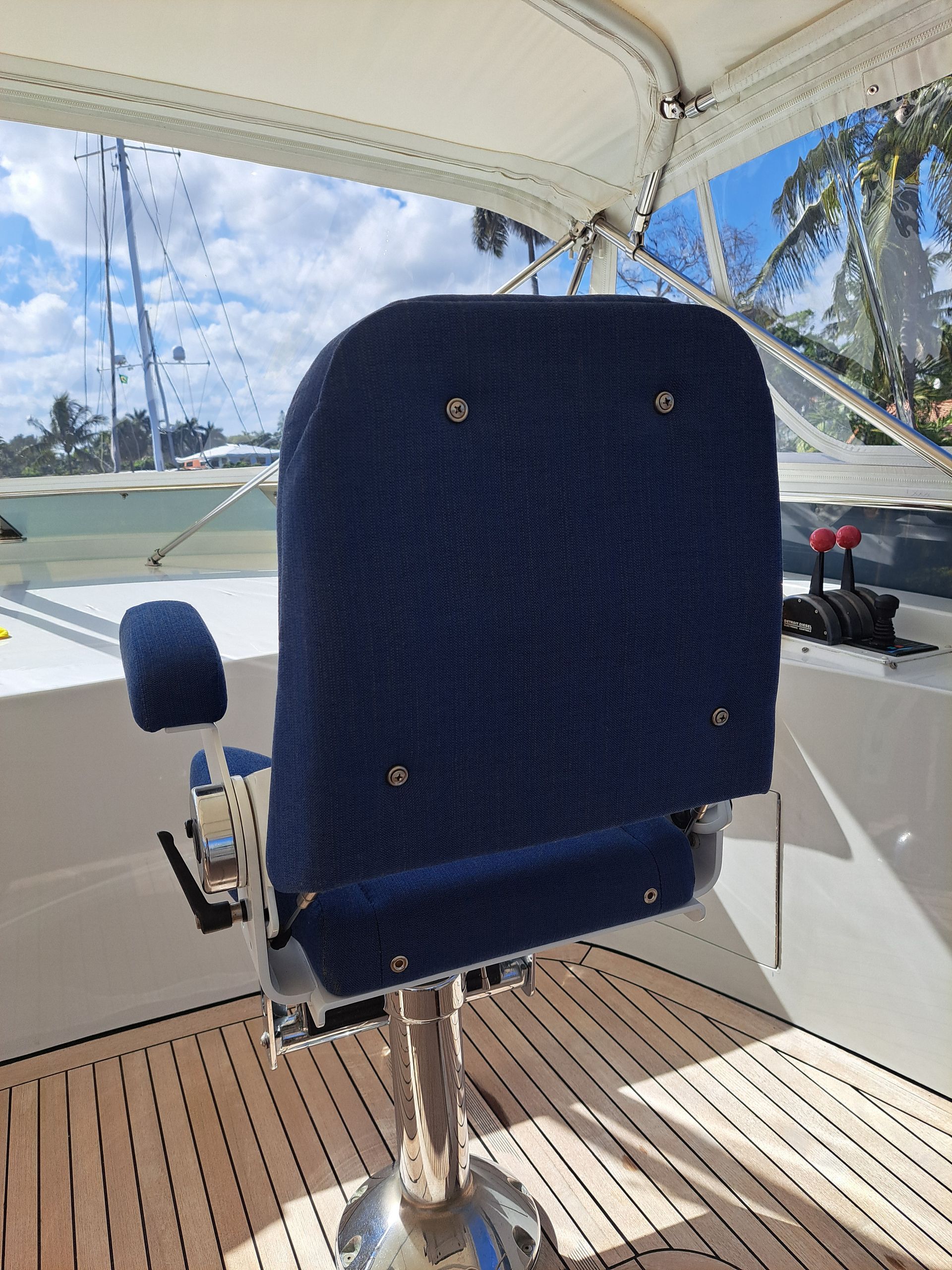 Blue upholstered captain's chair on a boat deck, with a clear windscreen and controls visible.