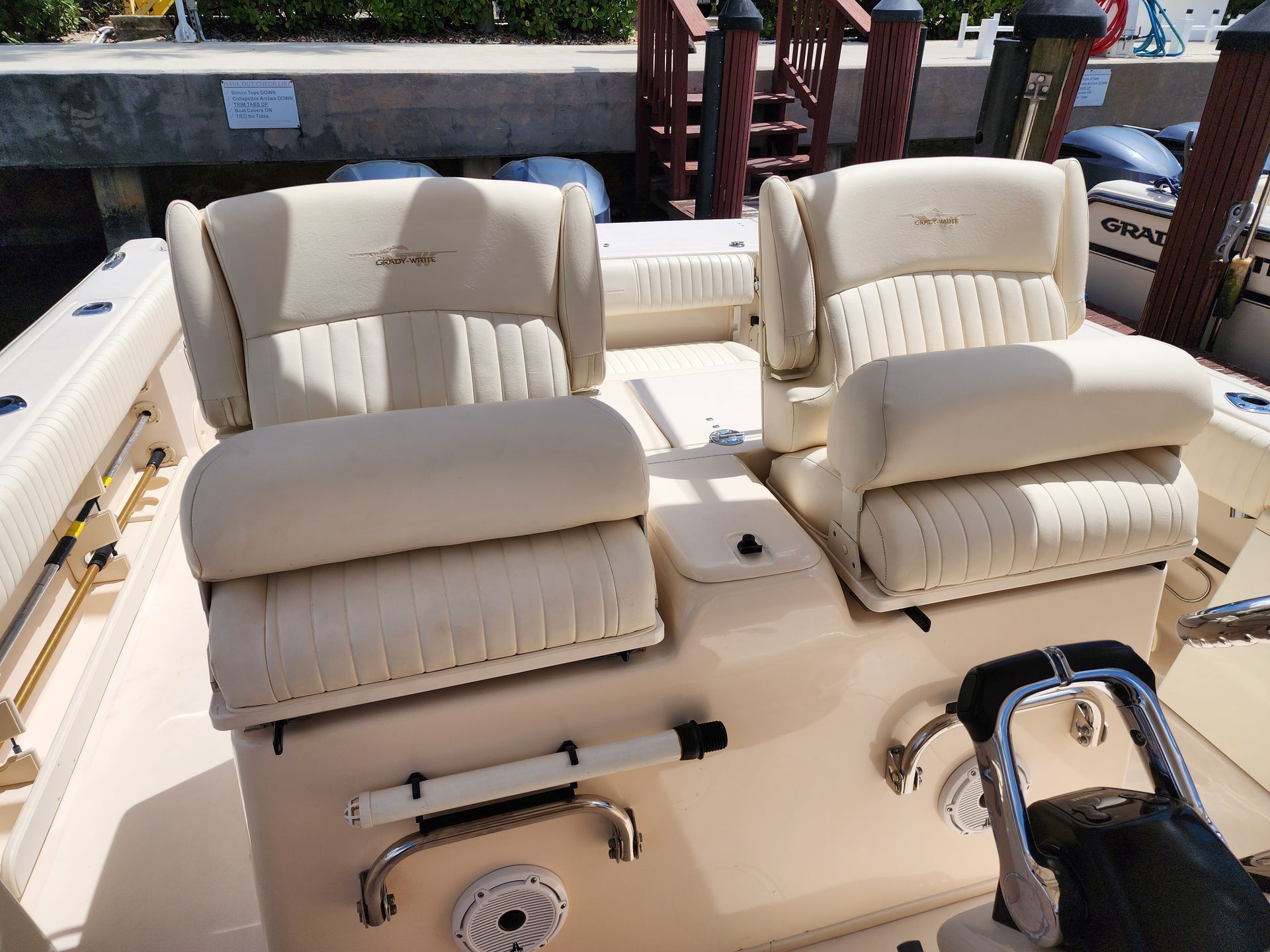 Two cream-colored boat seats with armrests, facing forward, on a light-colored boat deck.