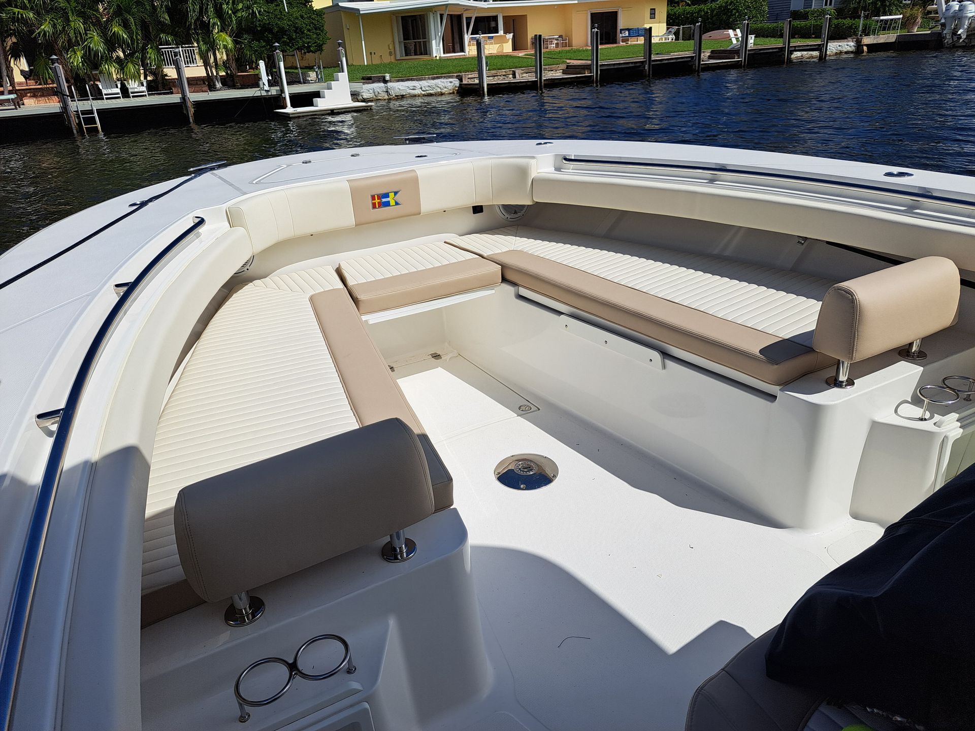 Interior of a boat with tan and white seating, in a waterway setting.