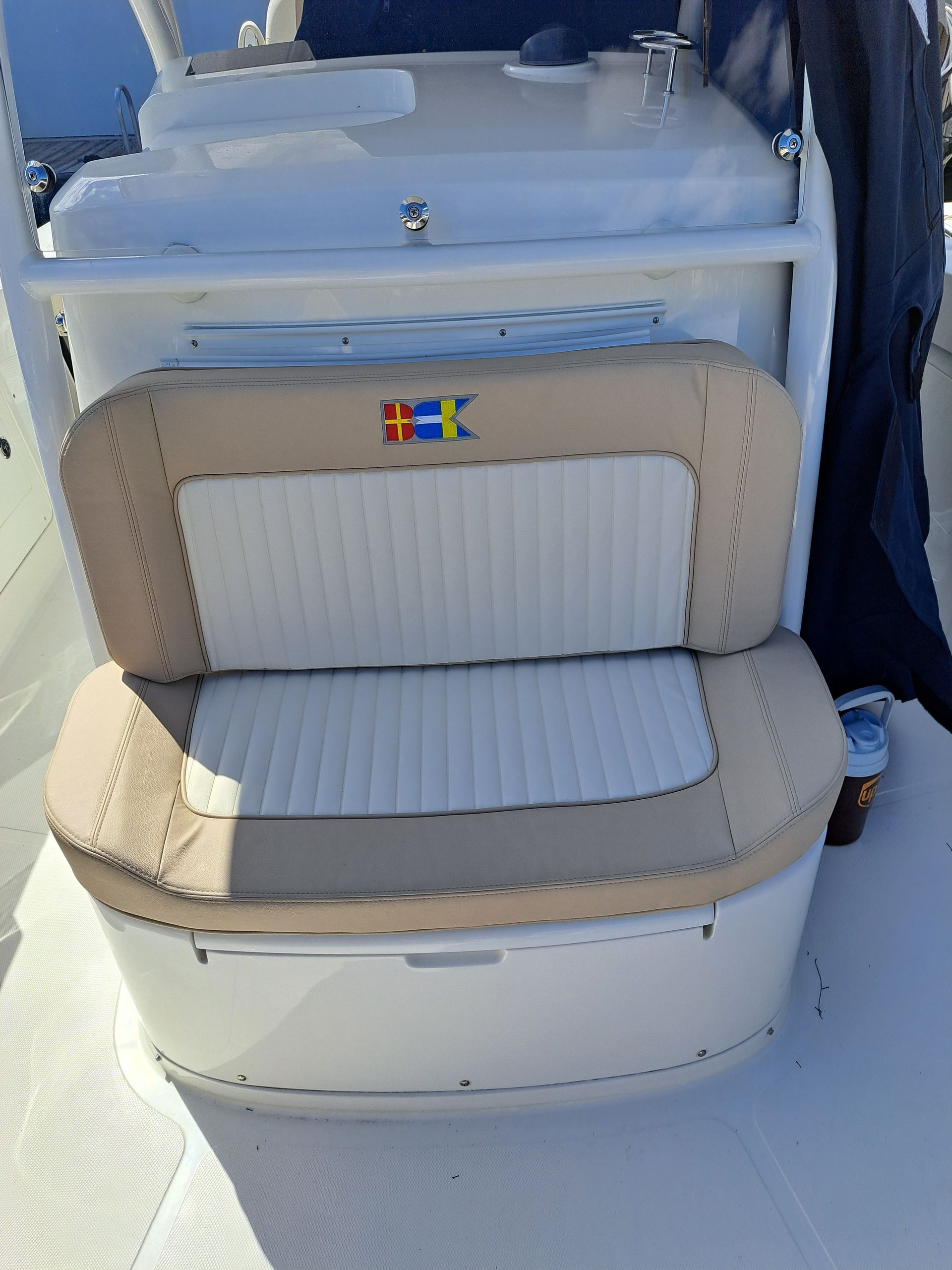 Boat seat with tan and white cushions, with logo and white trim.