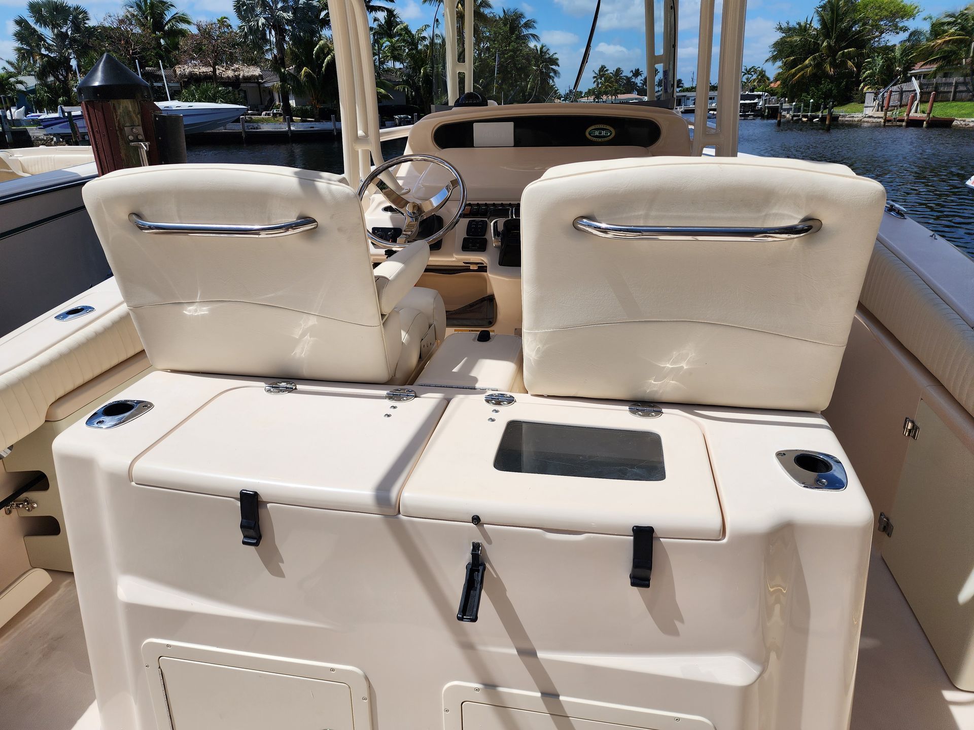 Boat cockpit interior with white seats and a steering wheel.