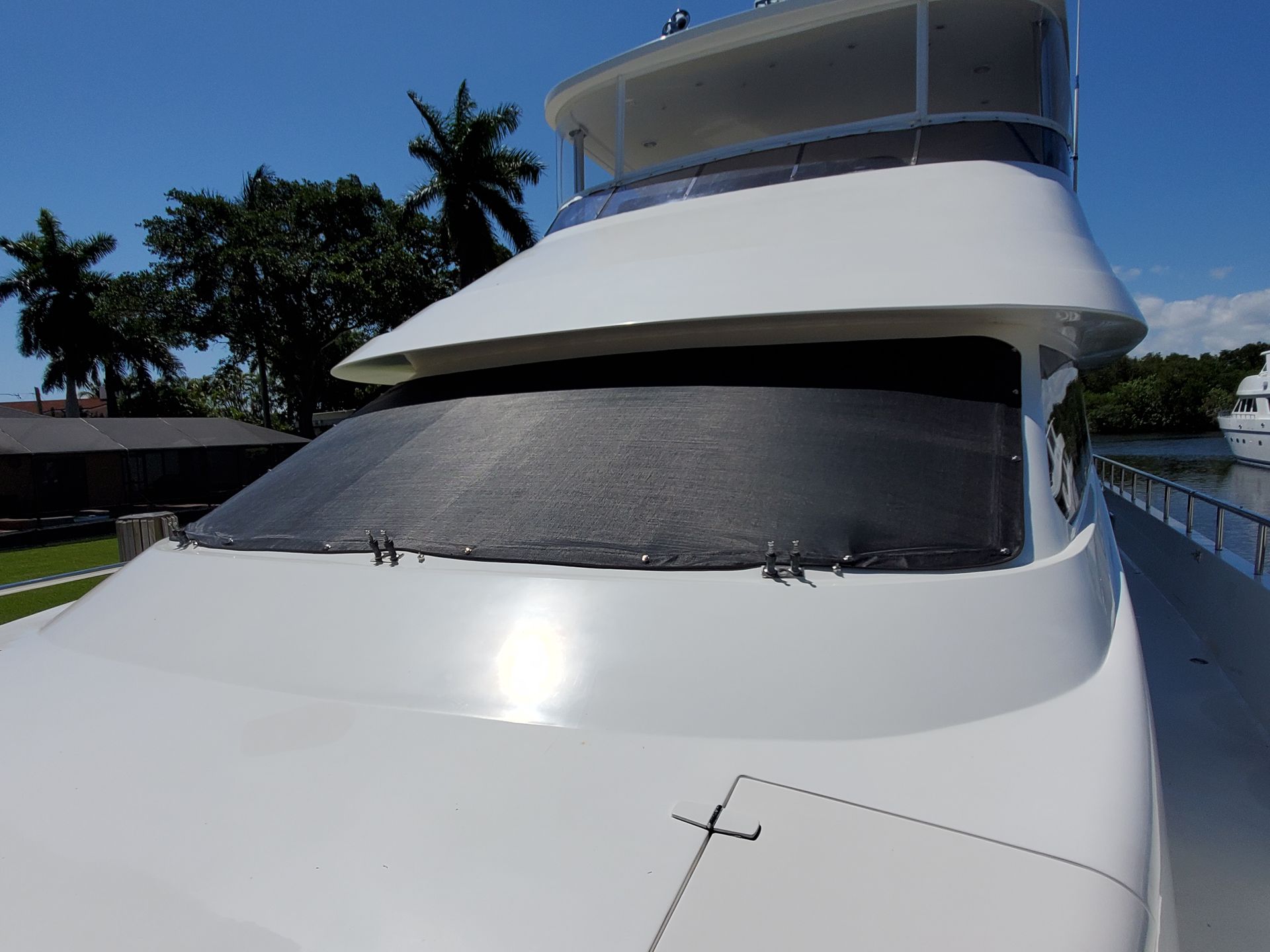 A large white yacht is docked in a marina with palm trees in the background