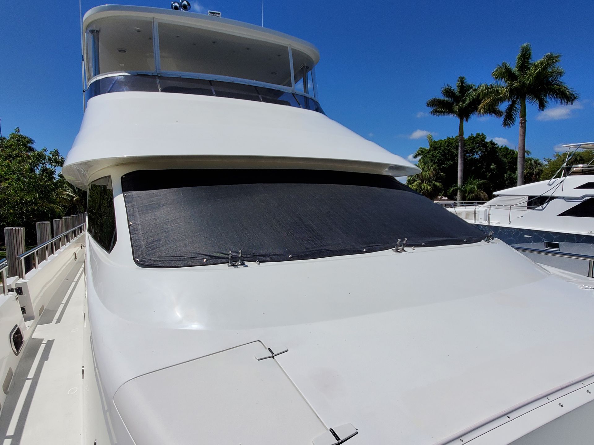 The front of a white yacht with palm trees in the background