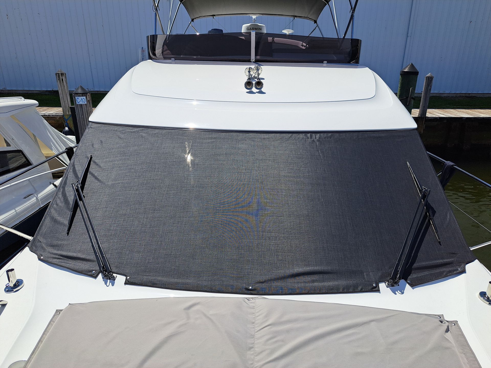 A white boat with a black cover on the windshield