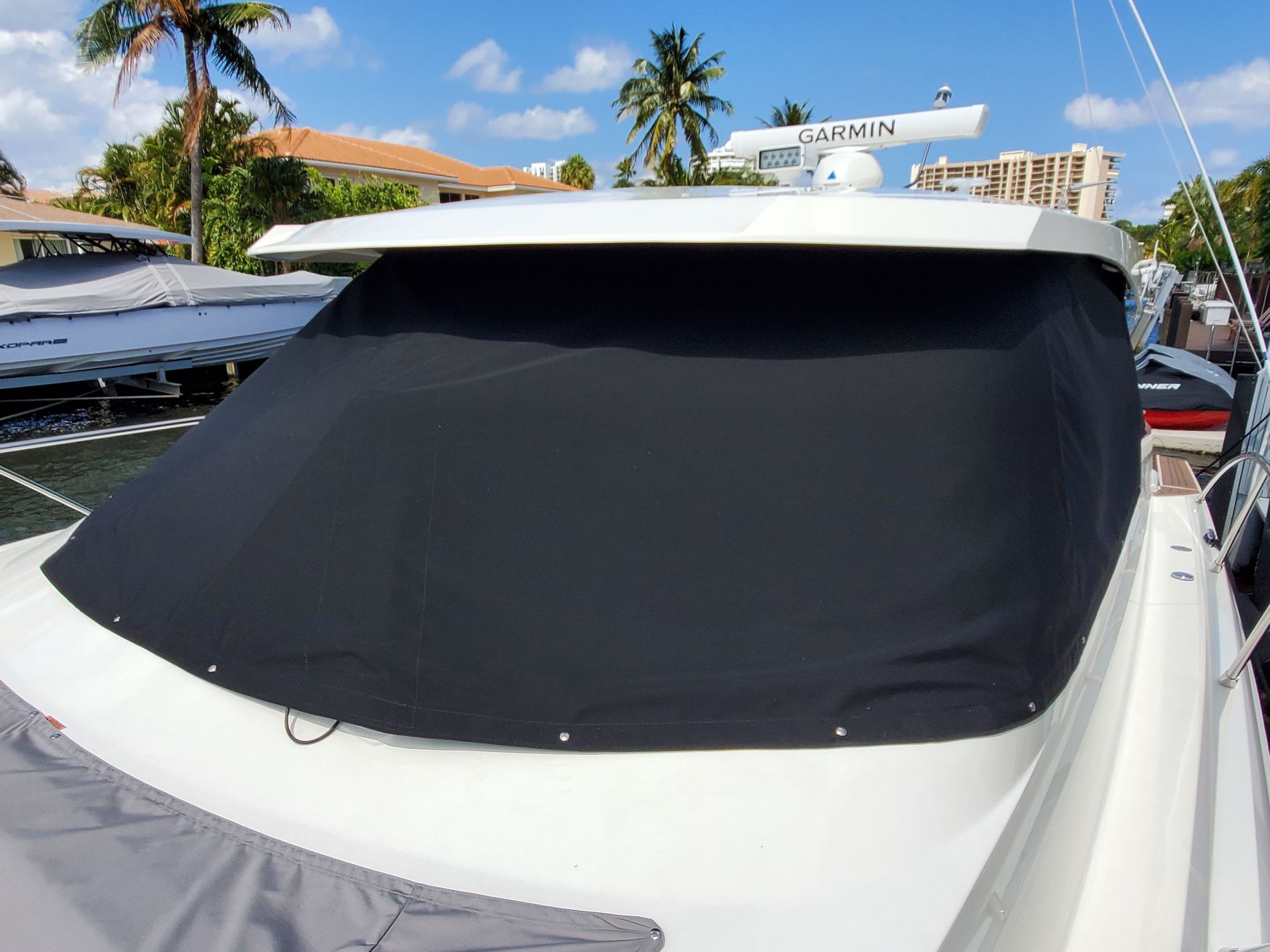 A white boat with a black cover on the windshield