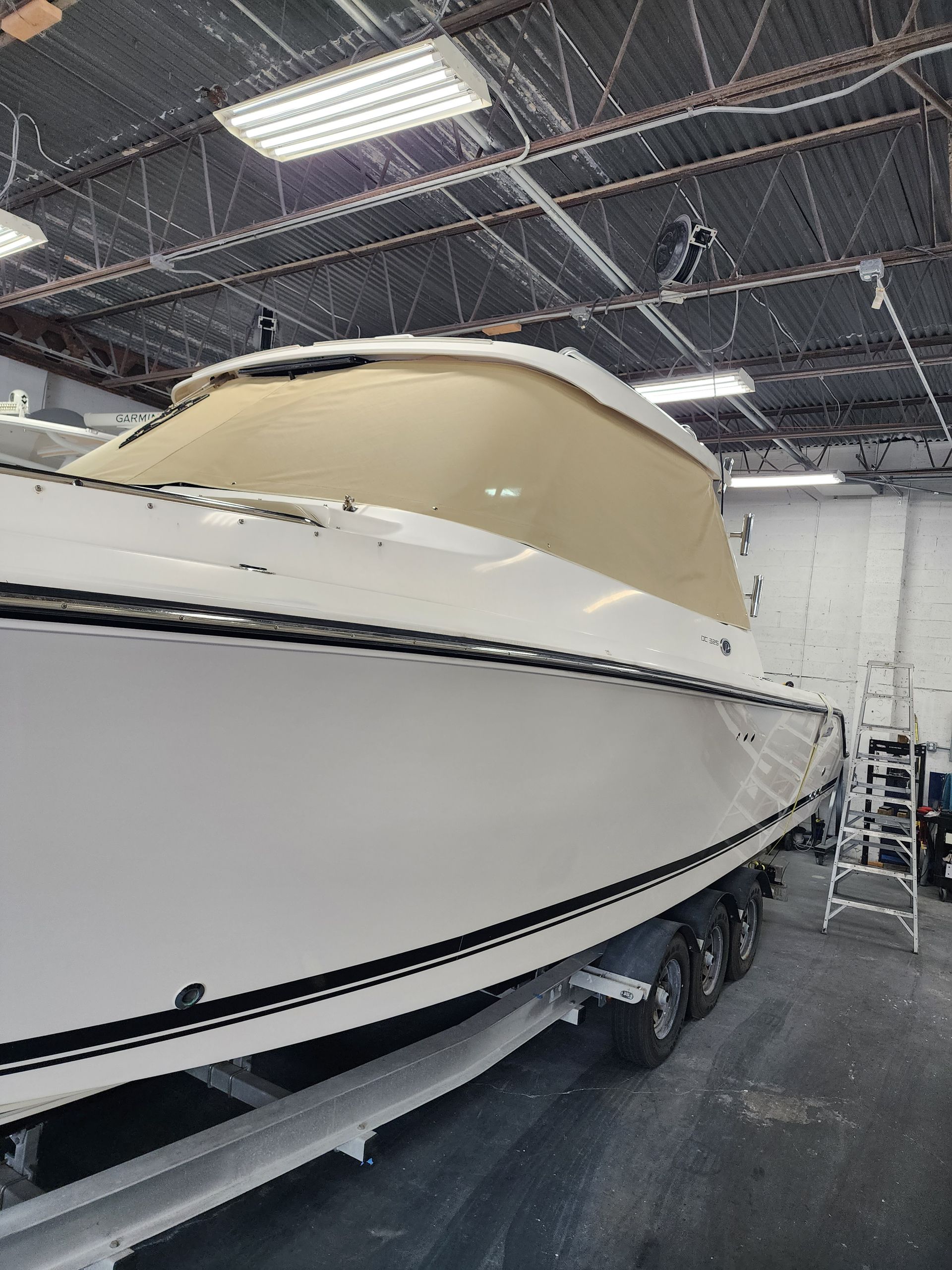 A white boat is sitting on a trailer in a garage.