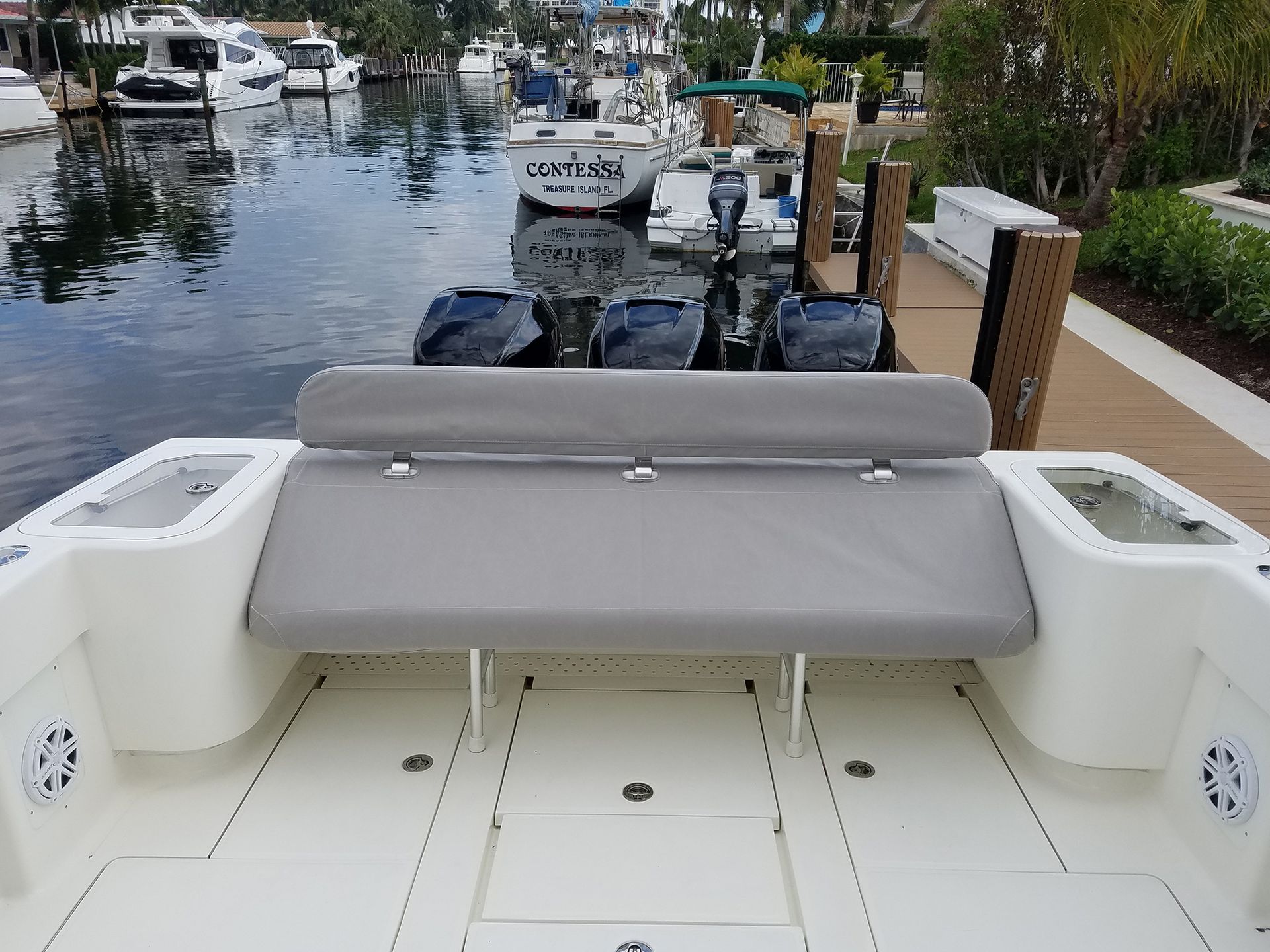 The back of a boat with a bench and a dock in the background.