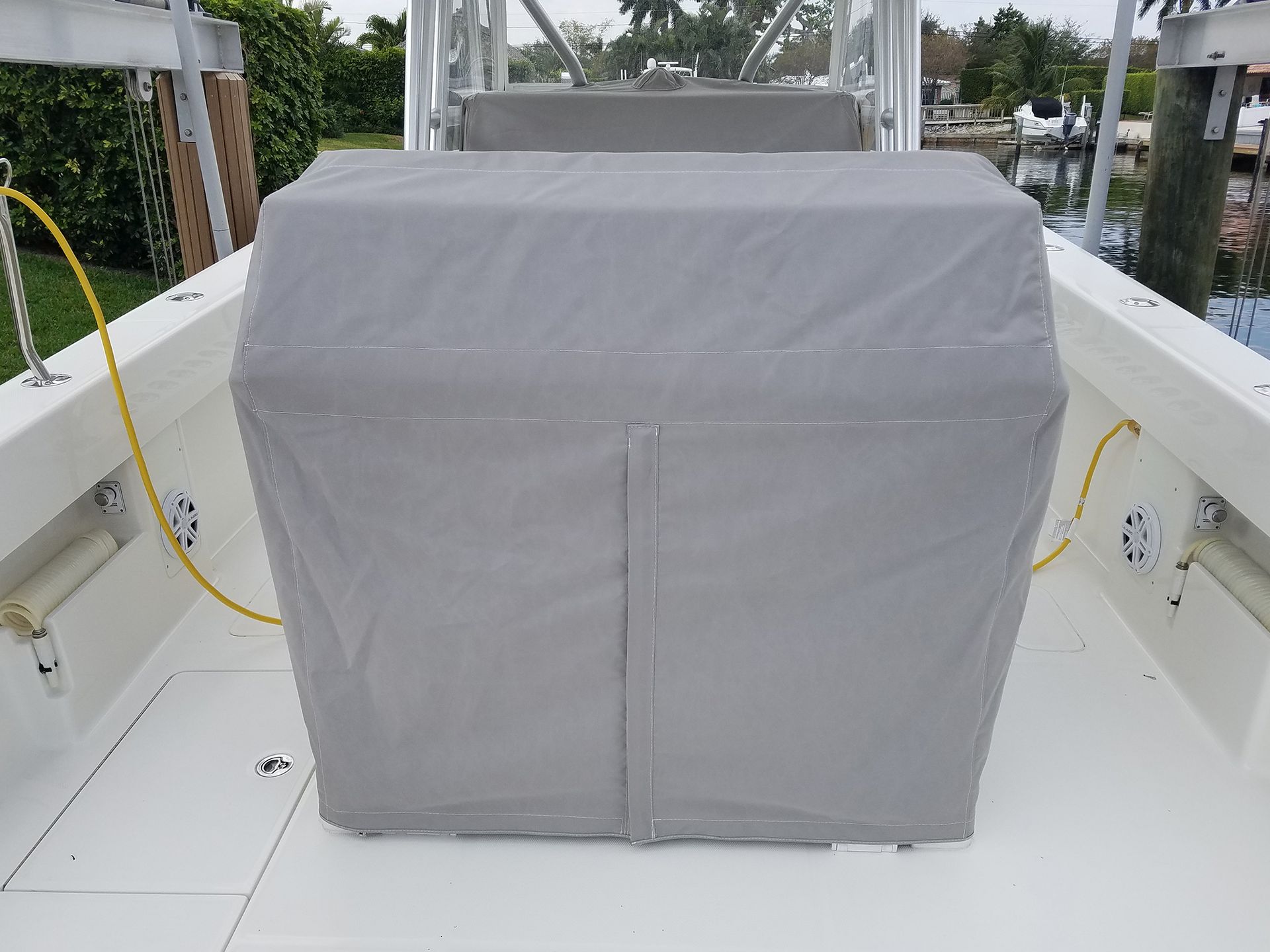 A white boat with a grey cover on the back of it.