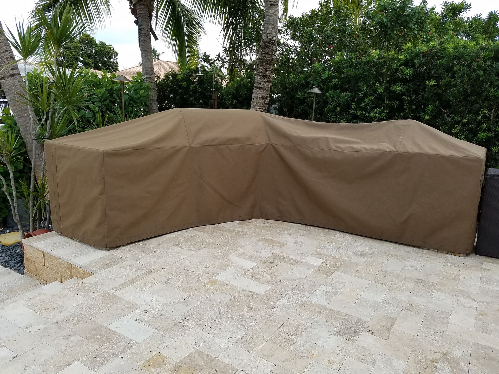 A brown patio furniture cover is sitting on a tiled patio.