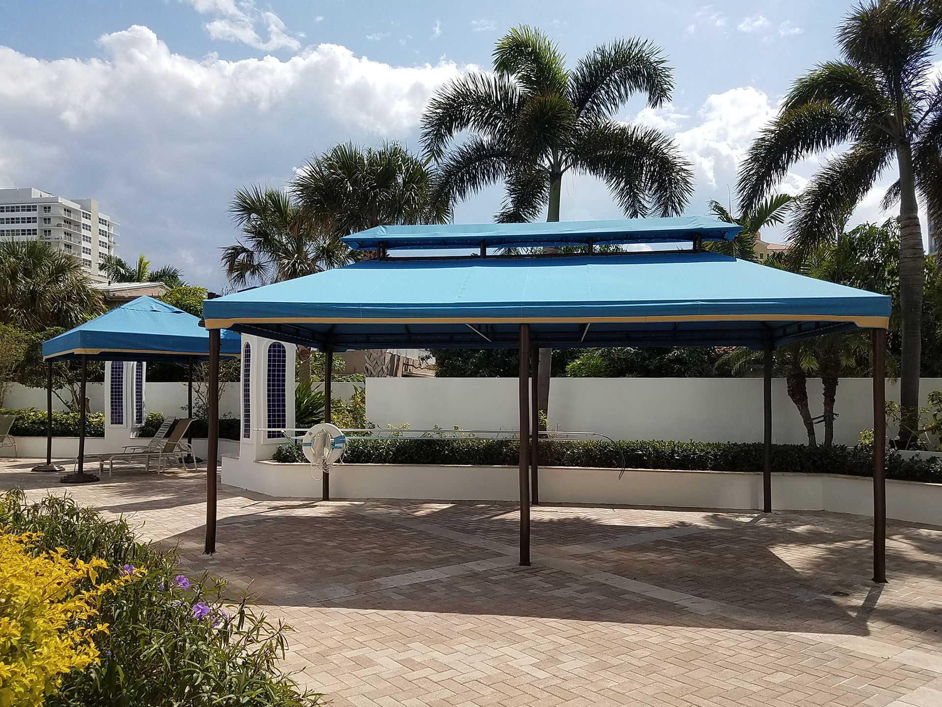A gazebo with a blue roof is surrounded by palm trees