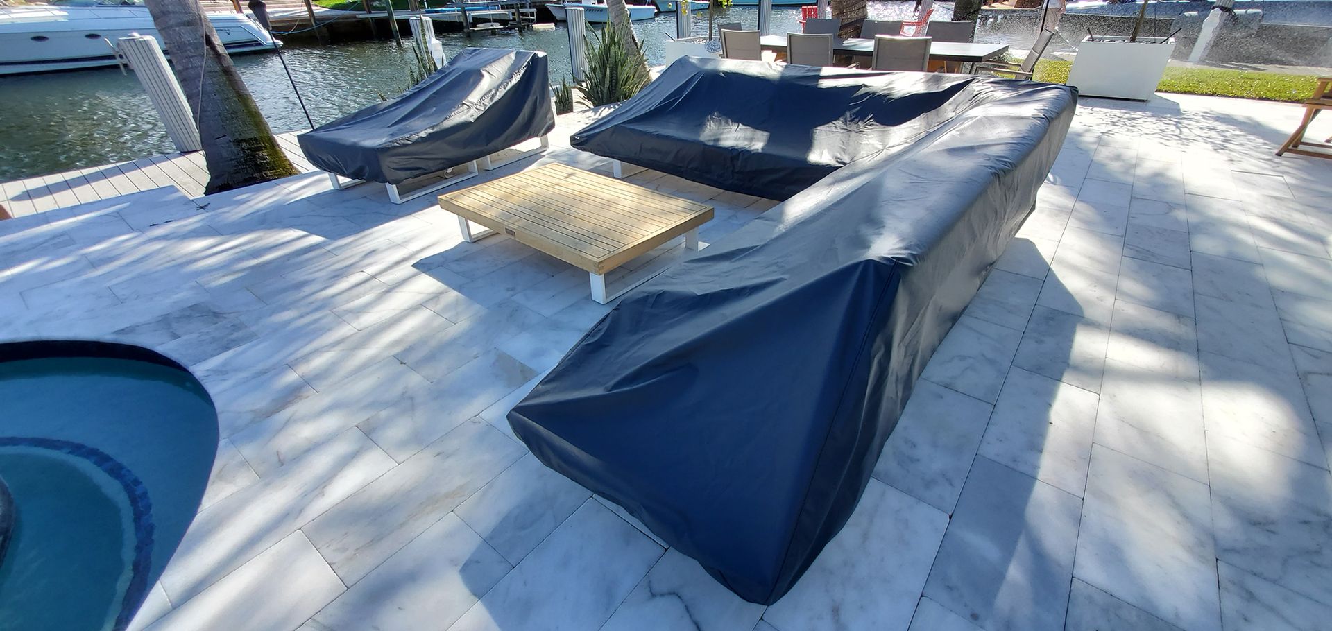 A patio with a couch and chairs covered in a black cover.