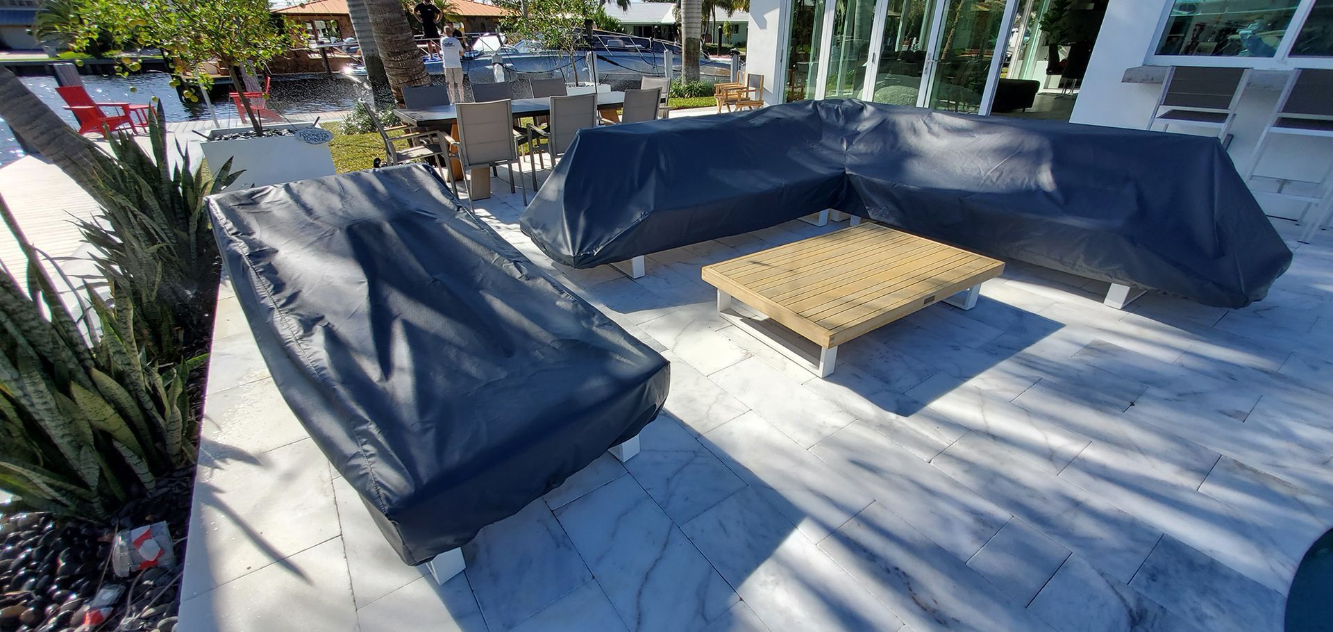 A patio with a lot of furniture and a table covered in black plastic.