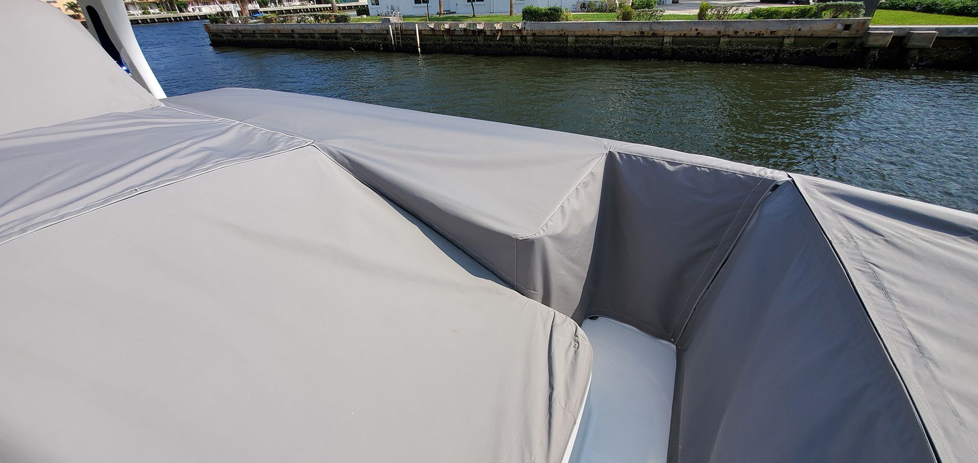 A boat with a cover on it is sitting next to a body of water.