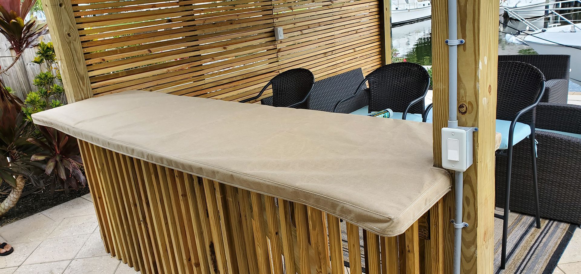 A wooden bar is sitting under a wooden pergola on a patio.