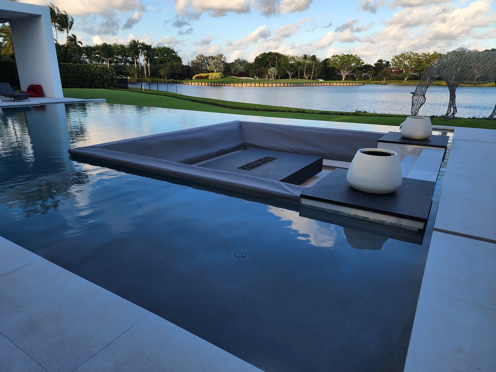 A large swimming pool with a fire pit in the middle