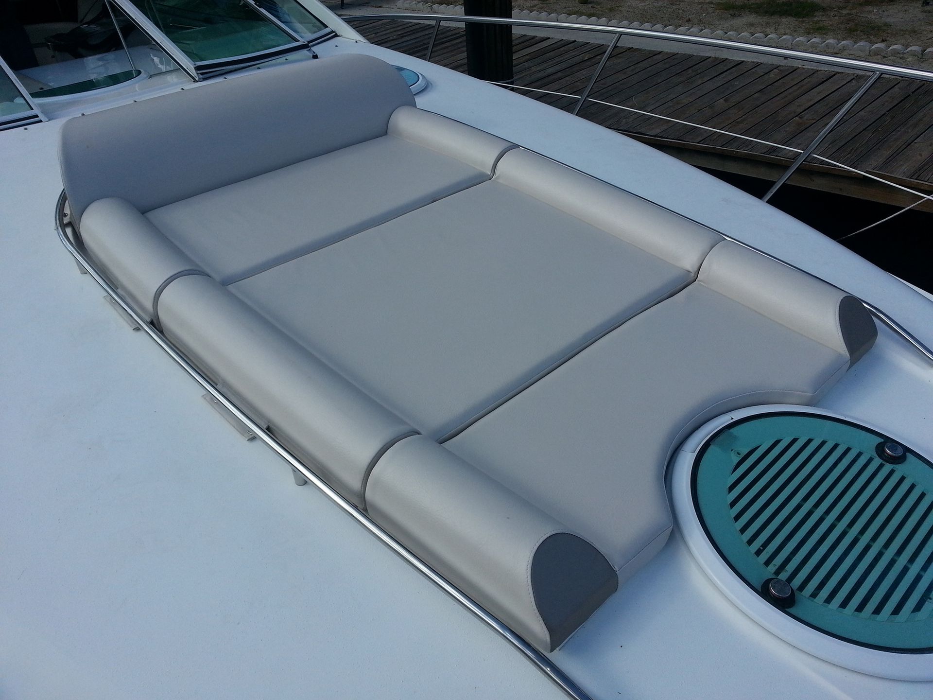 A white boat with a gray cushion on the back