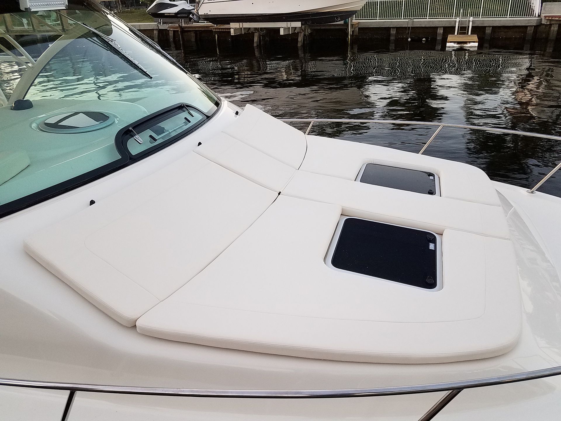 A white boat is docked in the water with a dock in the background