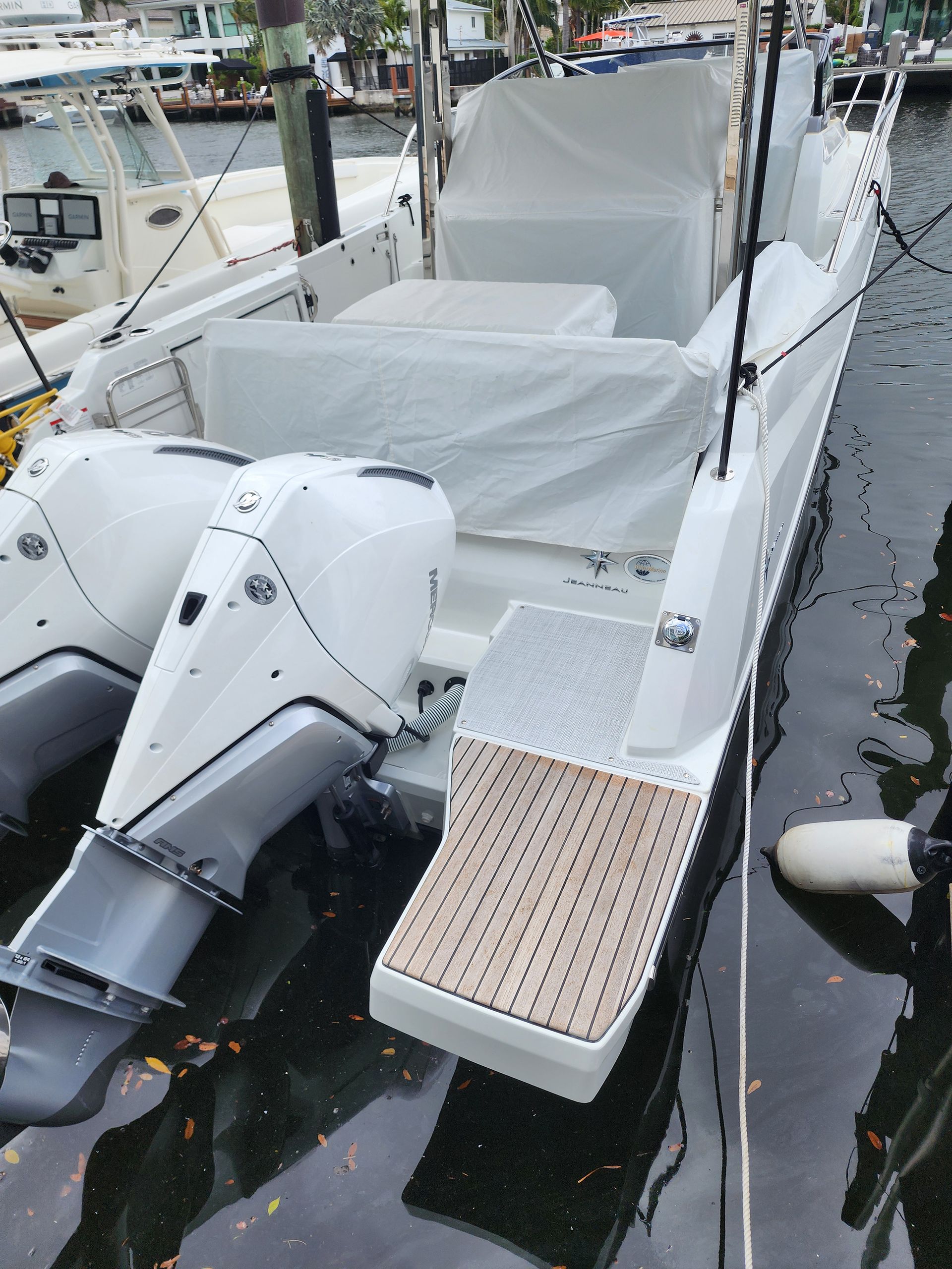 A white boat with a wooden deck is docked in the water