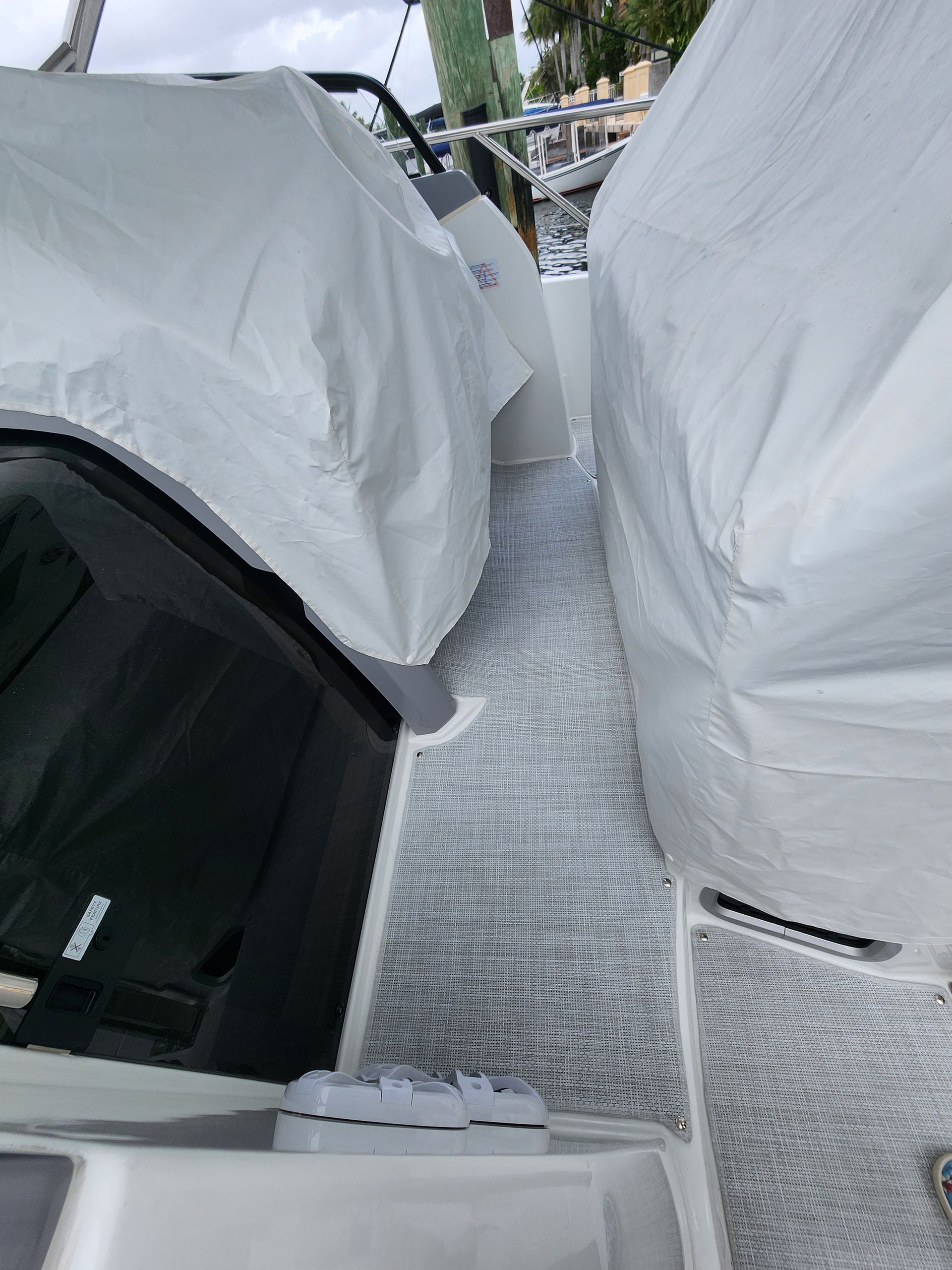 A boat with a white cover on it is parked next to another boat.