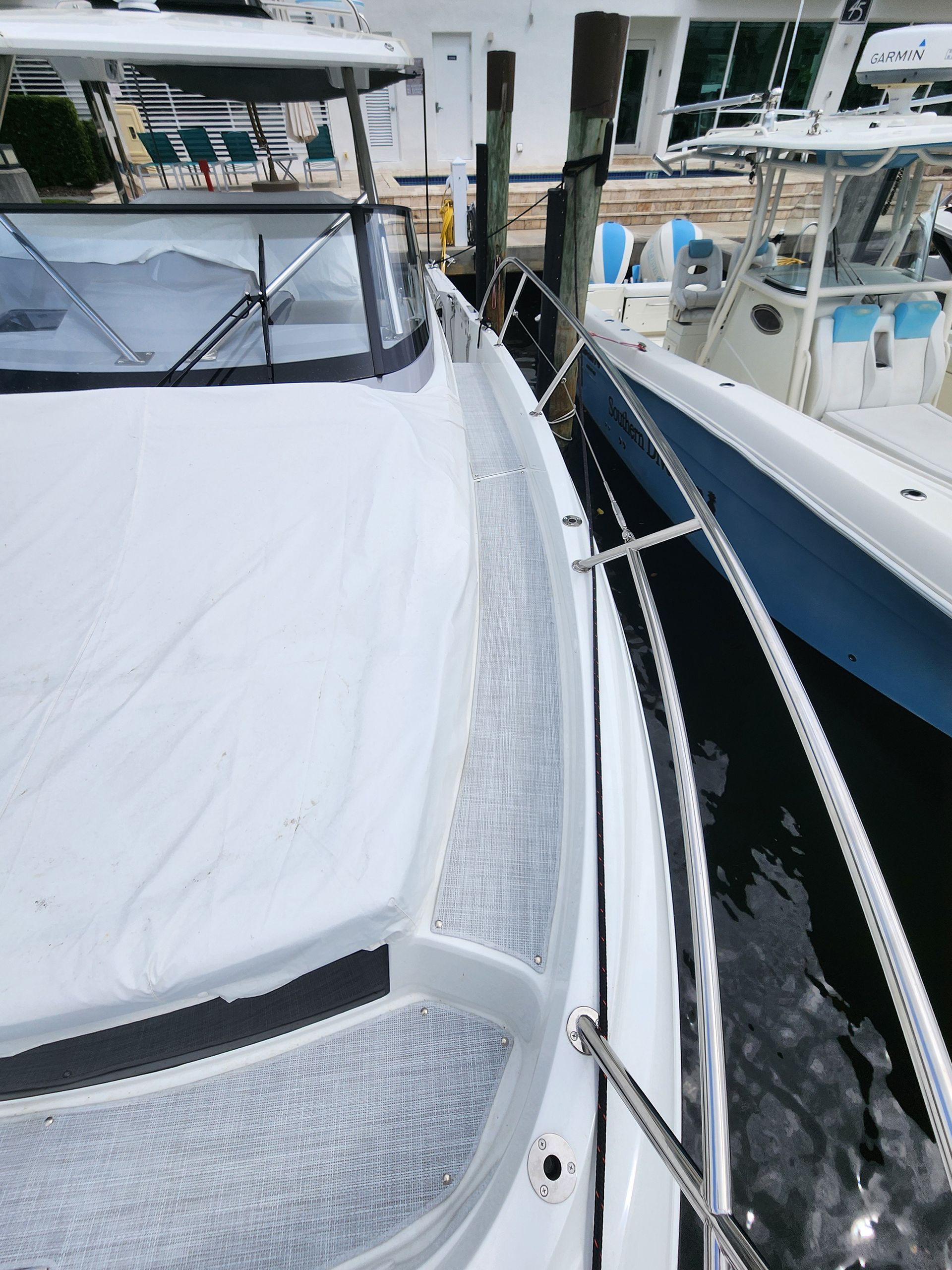 A white boat is docked in a marina next to a blue boat.