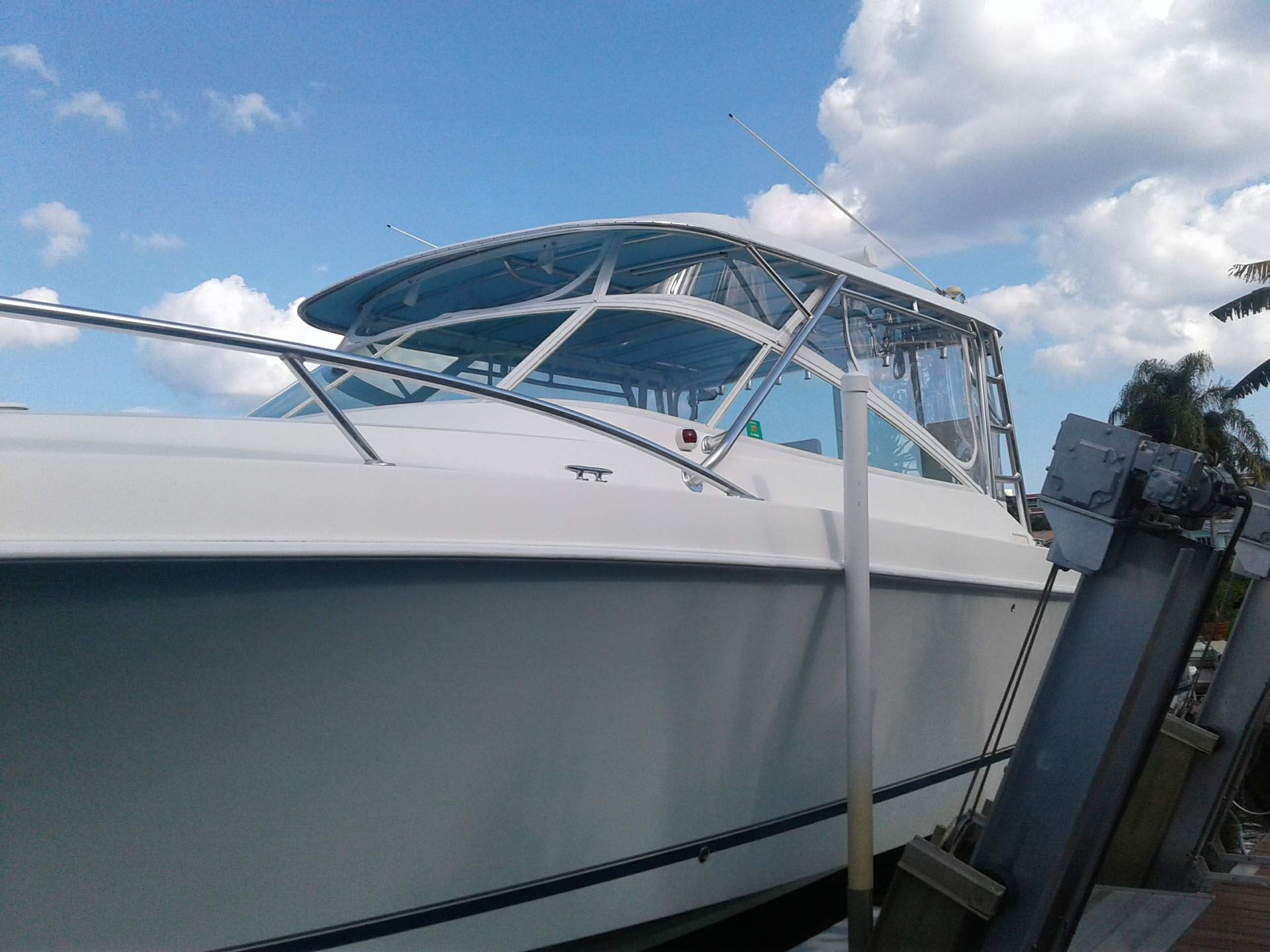White boat docked on a sunny day with blue sky, clear enclosure, and metal supports.
