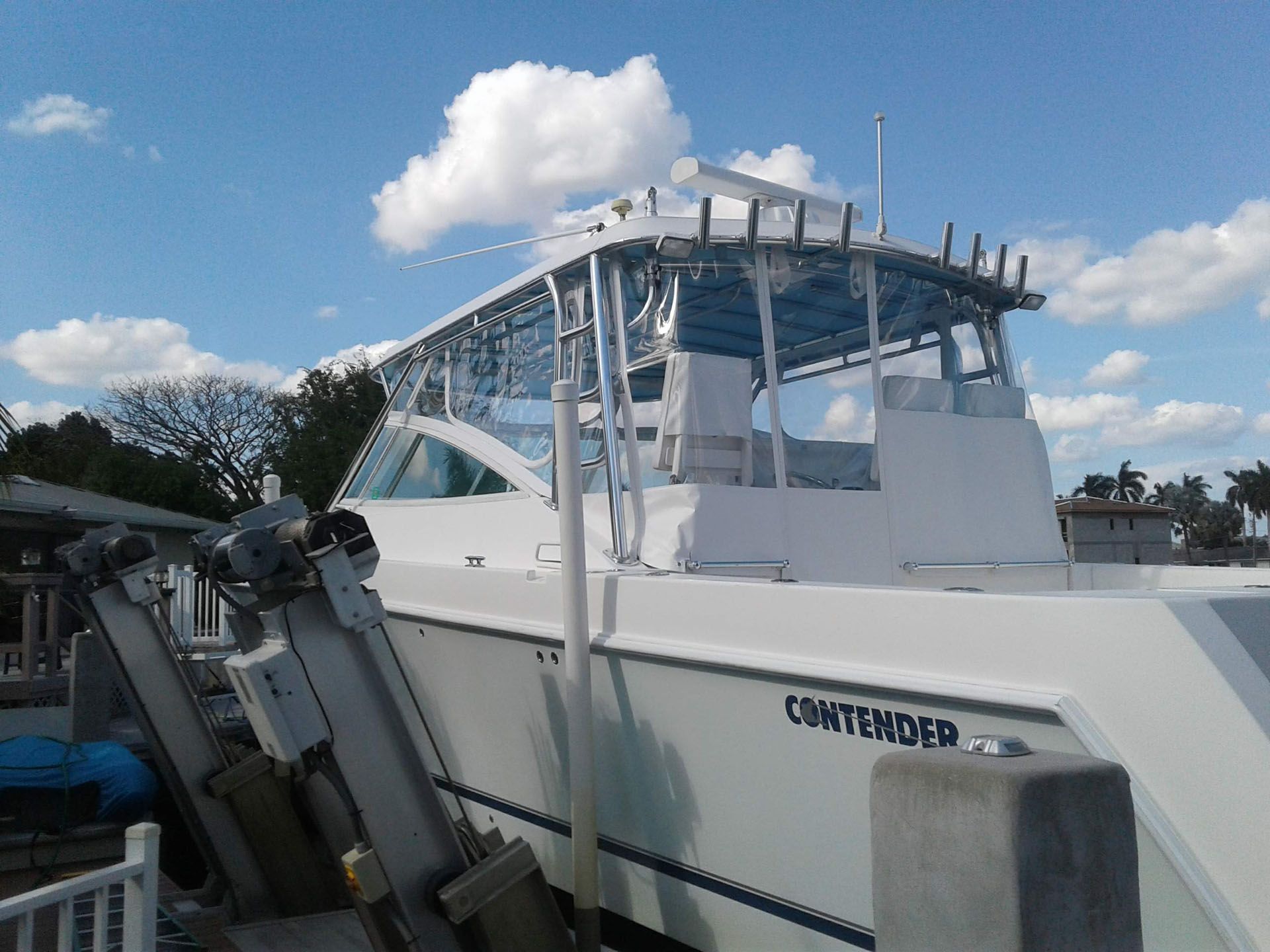 White Contender boat docked on a sunny day with a blue sky and fluffy clouds.