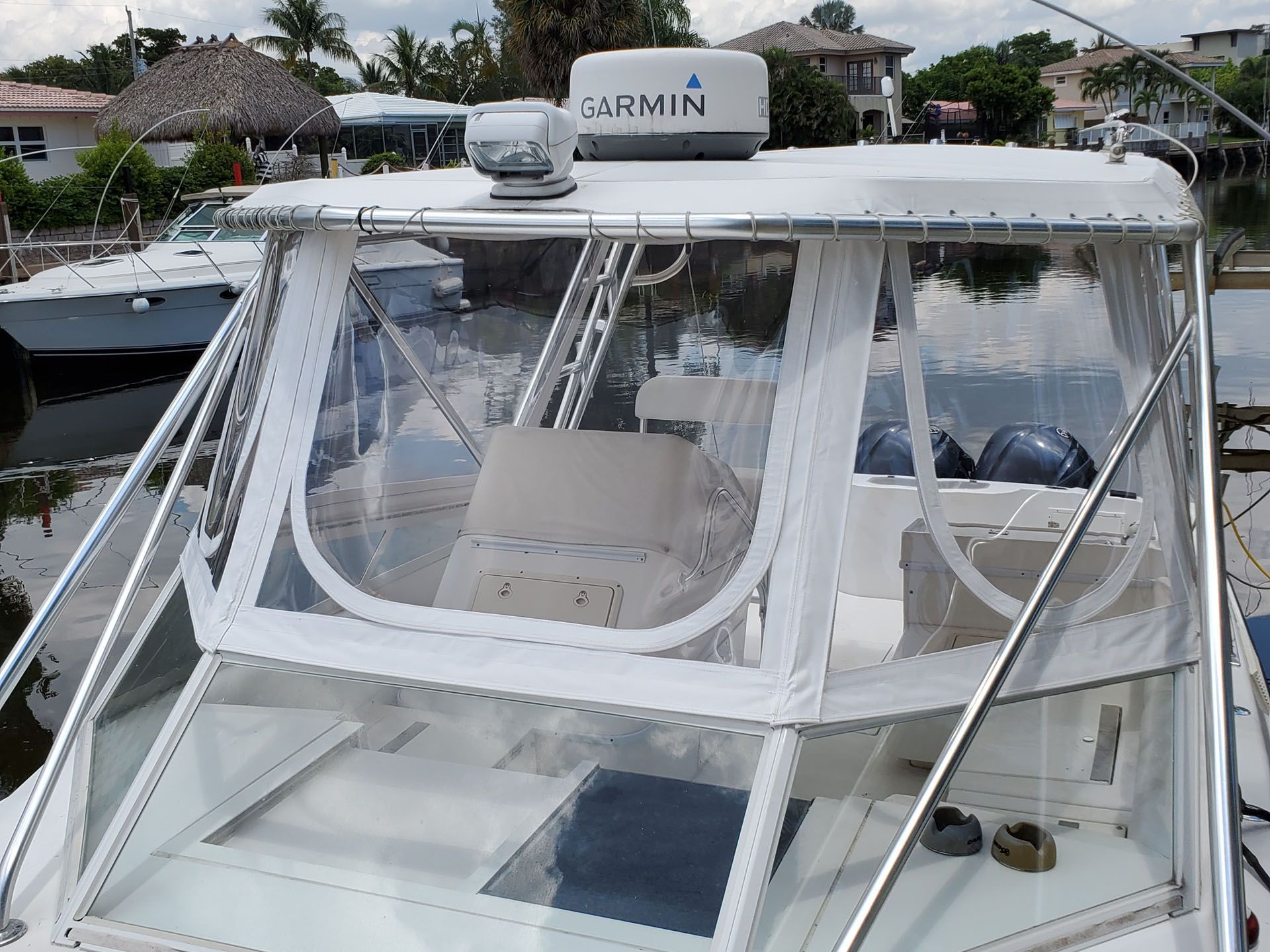 Boat cabin with clear vinyl enclosure, white frame, Garmin radar, and two seats.