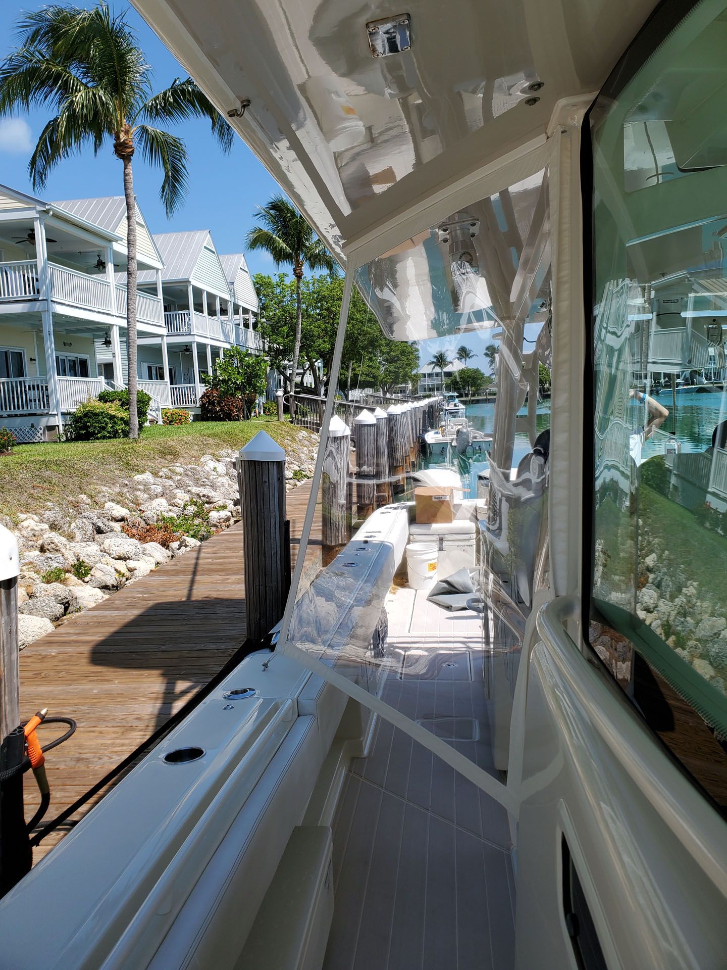 Boat docked at a pier, with buildings and palm trees in background.