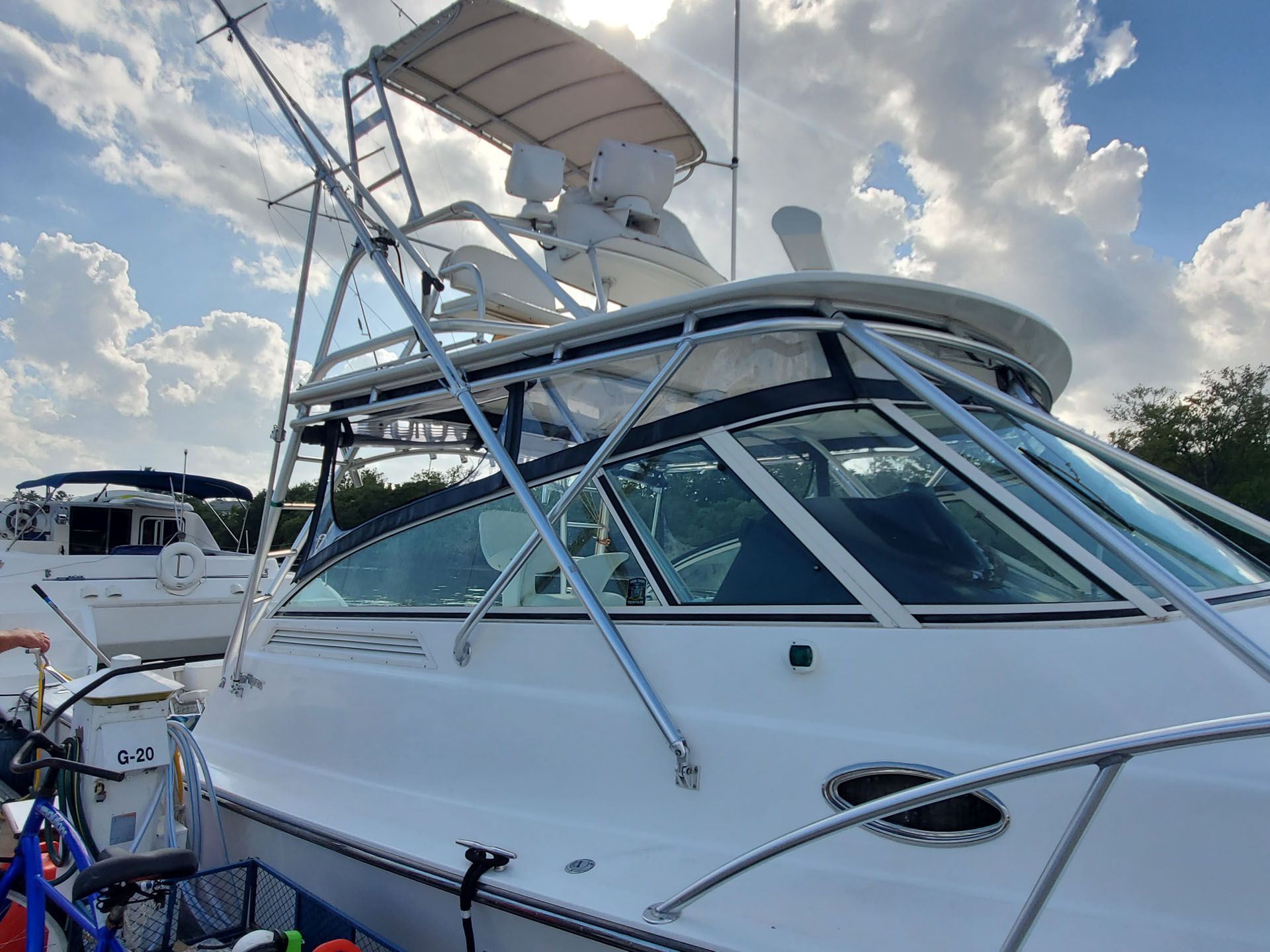White boat at a dock, with a radar tower, blue sky, and another boat in the background.