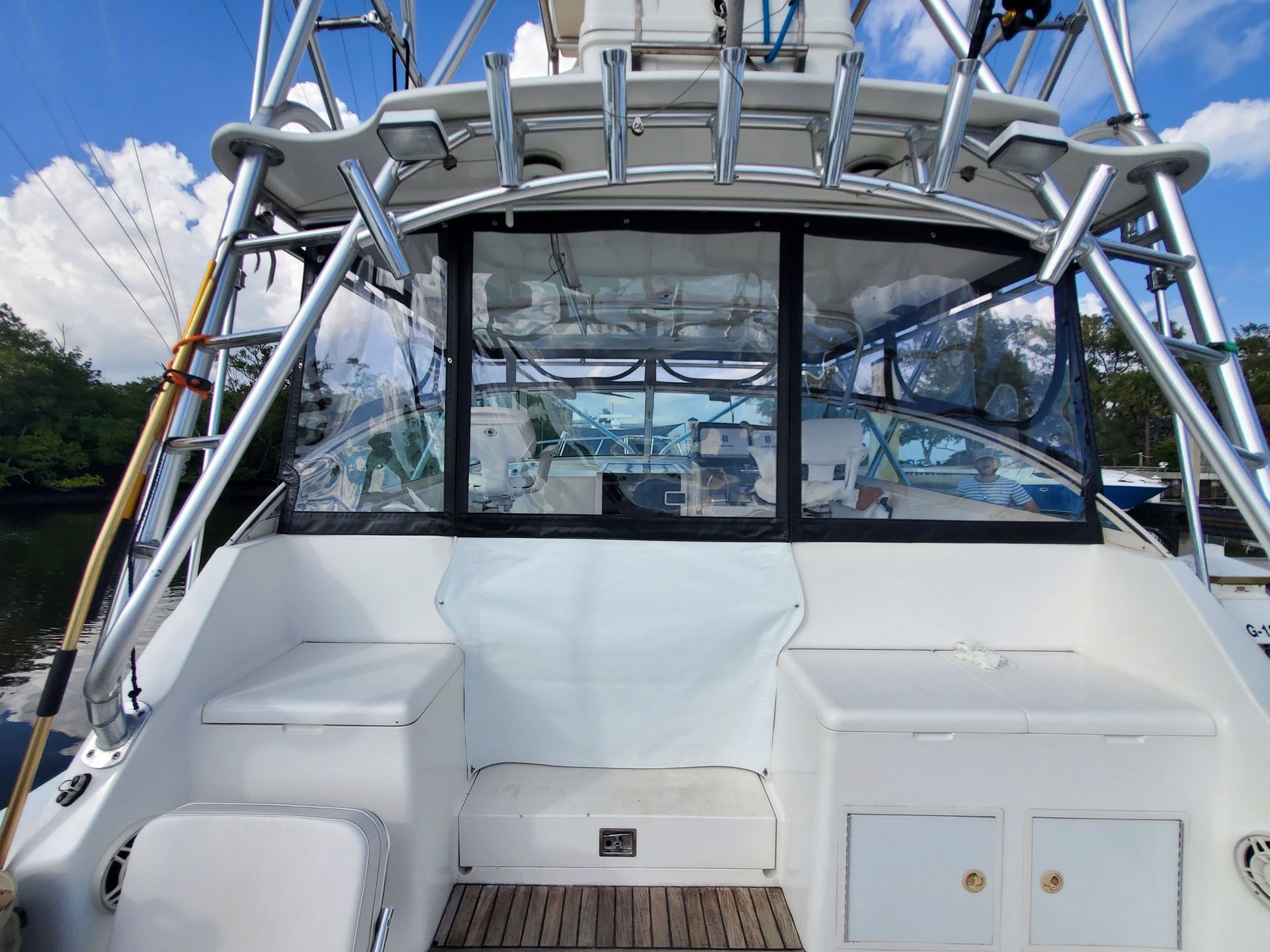 Stern of a white boat with clear windows, fishing rod holders, and a ladder.