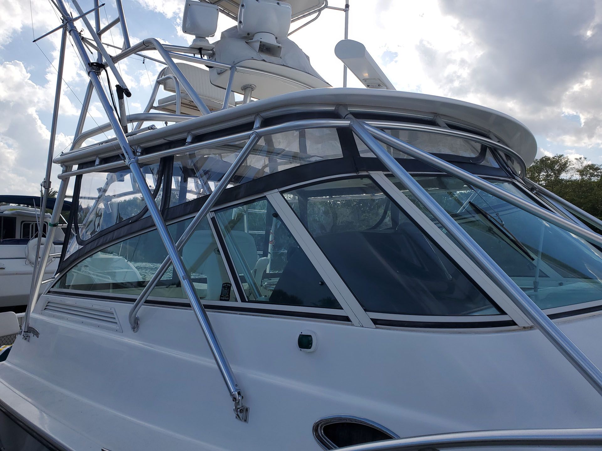 White boat with clear windshield, chrome railings, and a radar dome against a cloudy sky.