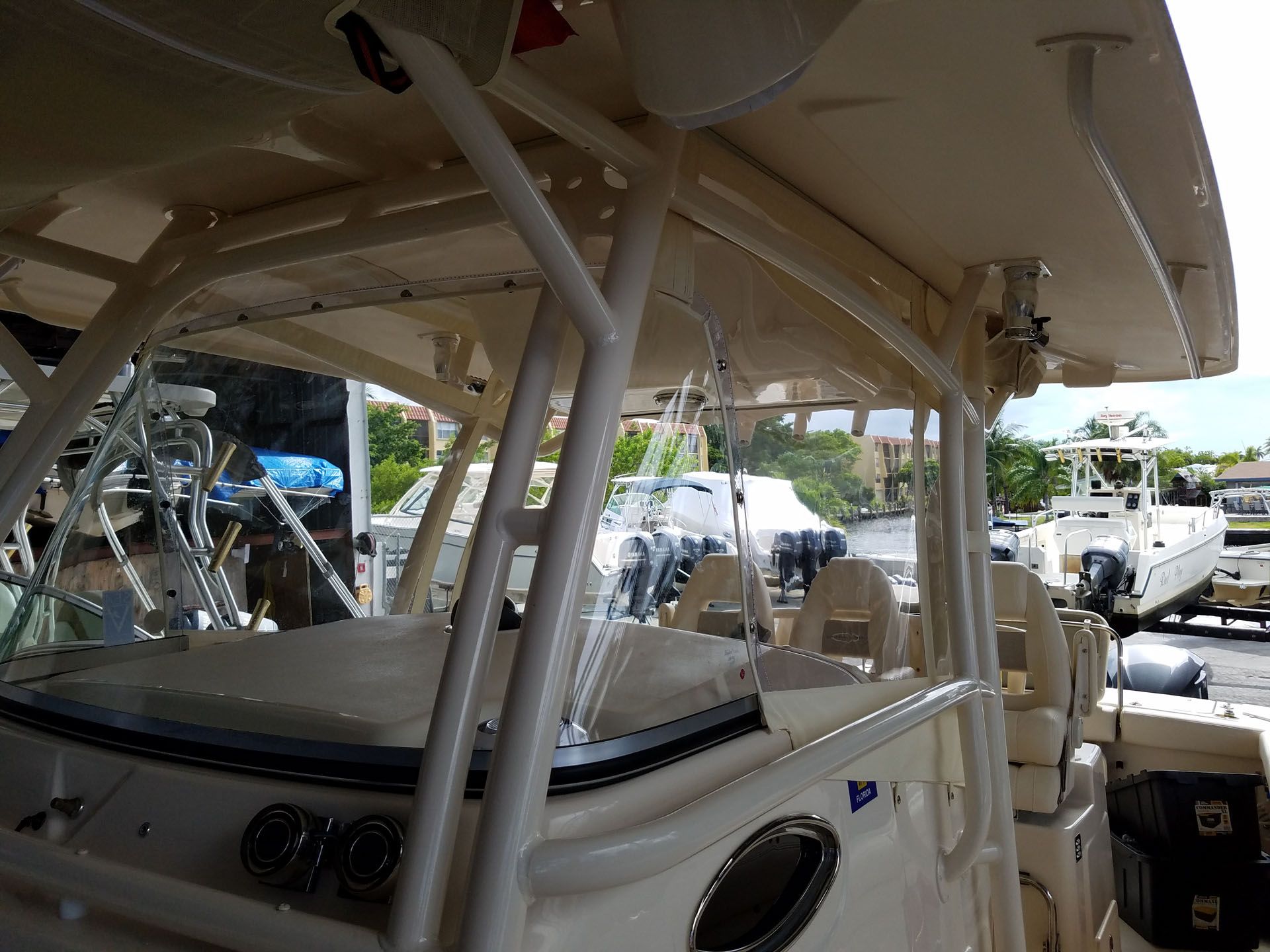 Interior view of a cream-colored boat with clear plastic windows and a metal frame, parked outside.