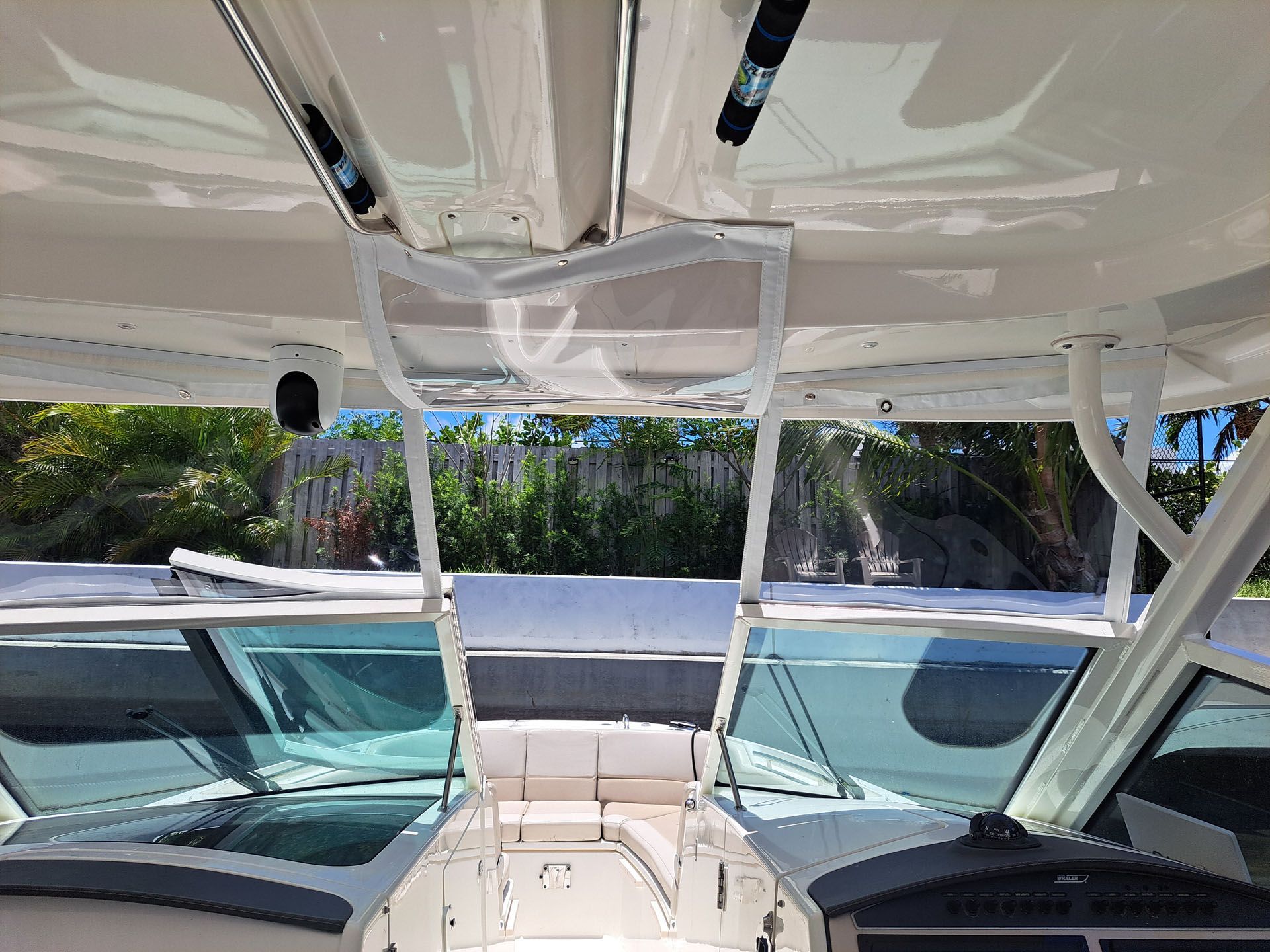 Interior of a boat cockpit with a windshield, seats, and a clear enclosure on the roof.