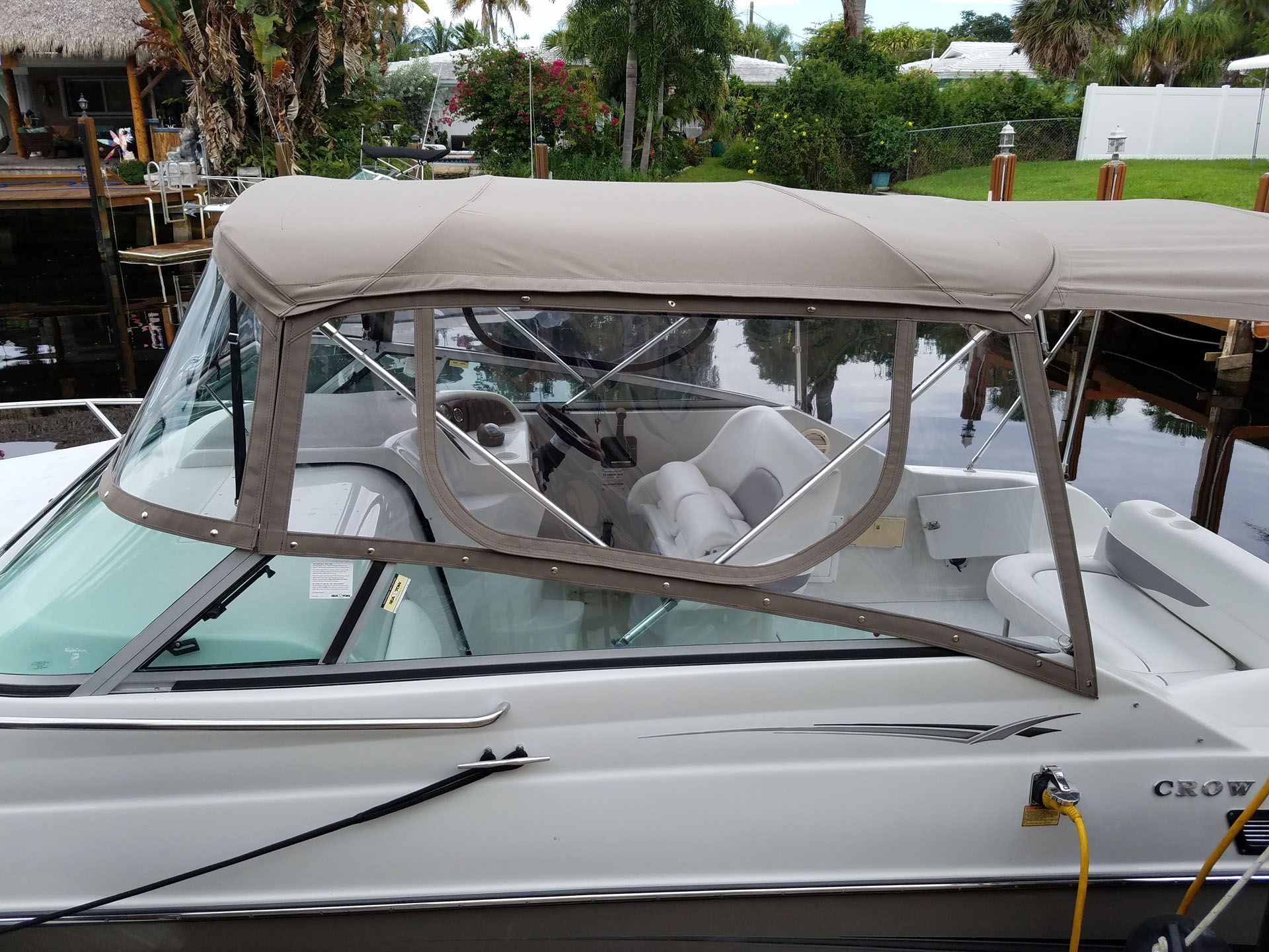 Tan-topped motorboat with clear side panels; docked on a waterway.