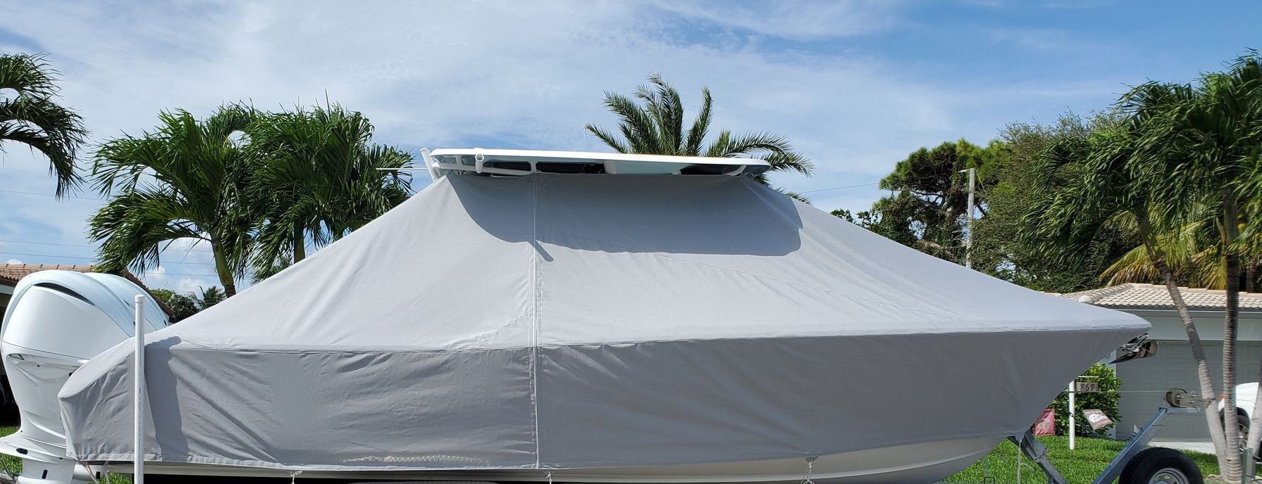 A blue boat is docked in a marina with palm trees in the background