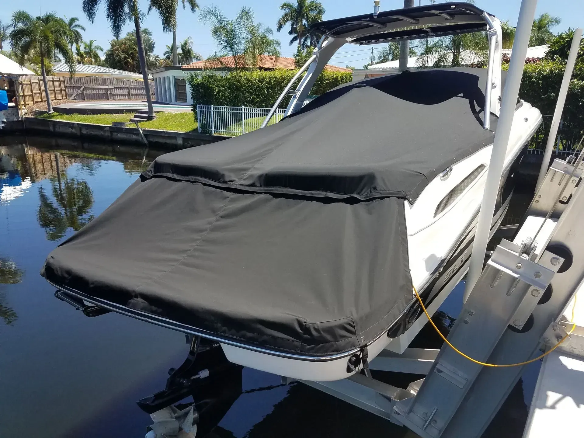 A black boat cover protects a white boat in a canal.