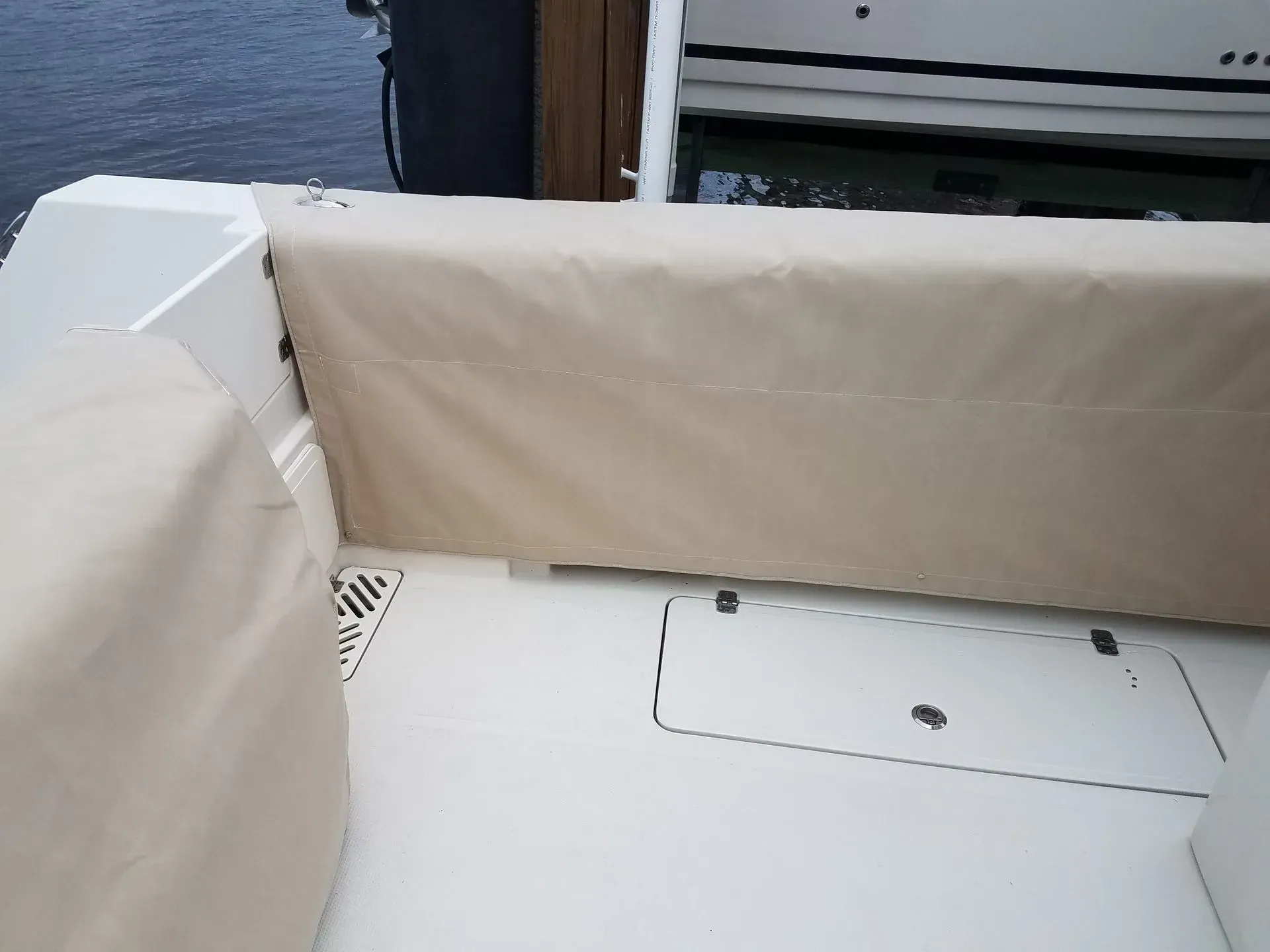 Boat interior, featuring a beige seat cover and white deck.