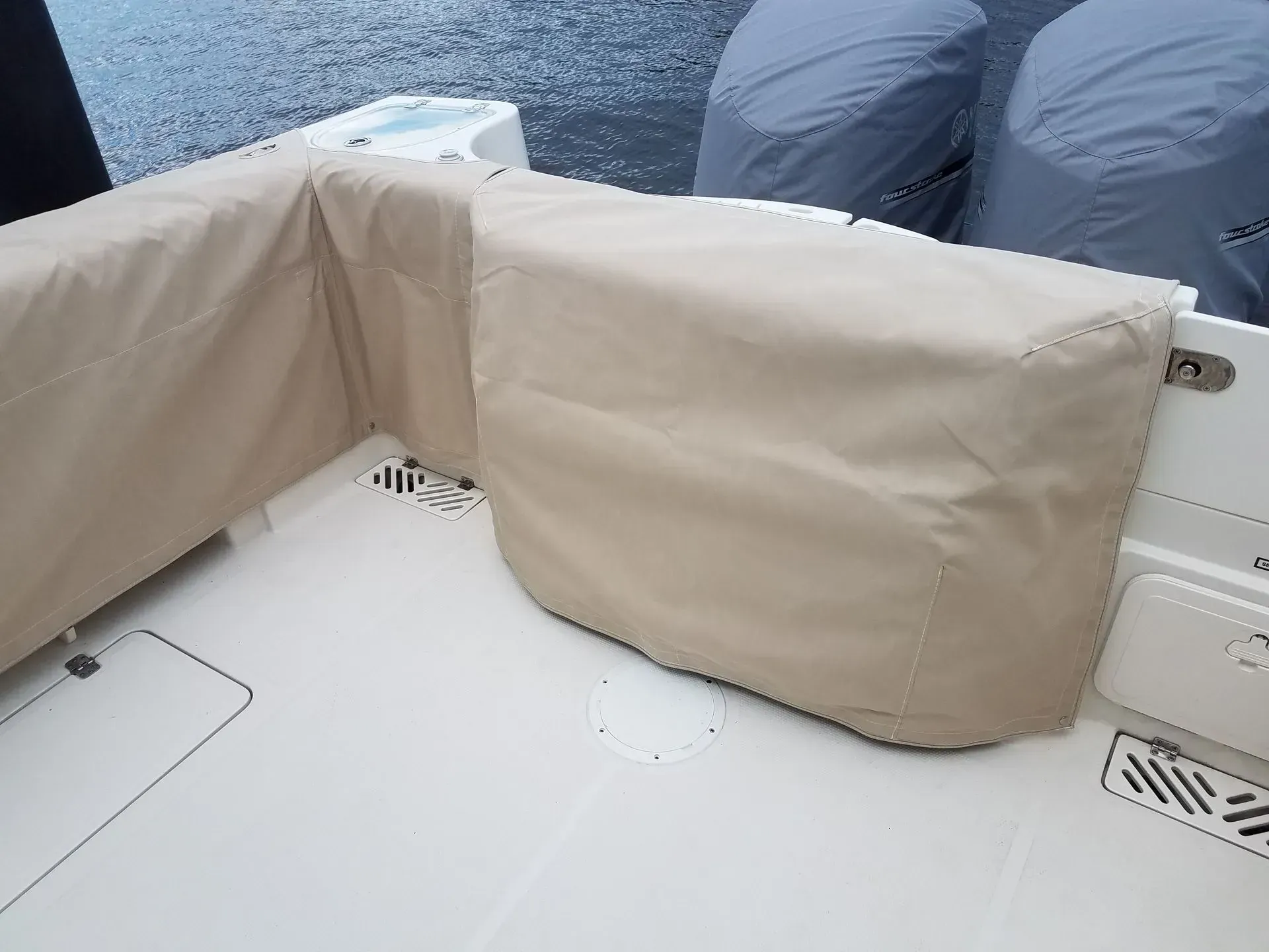 Tan boat cushions cover the stern seating area on a white boat. The motors are in the background.