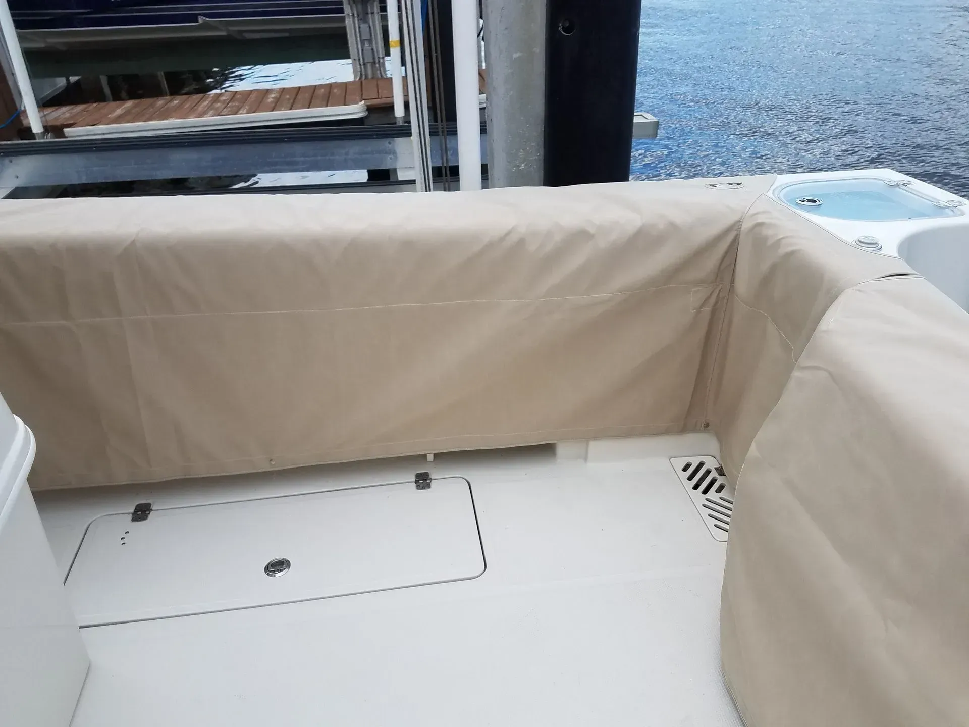 Tan boat cover over white boat deck near water.