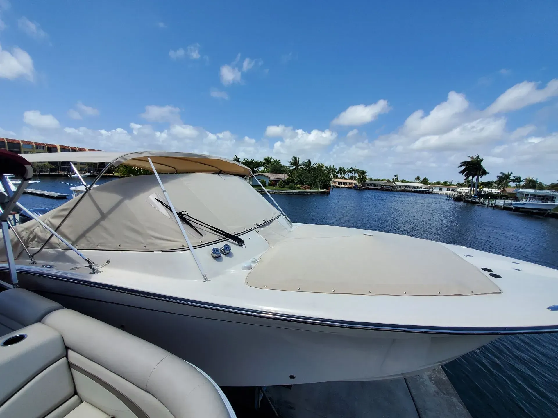 Boat docked on a sunny day with a beige sunshade and cover.