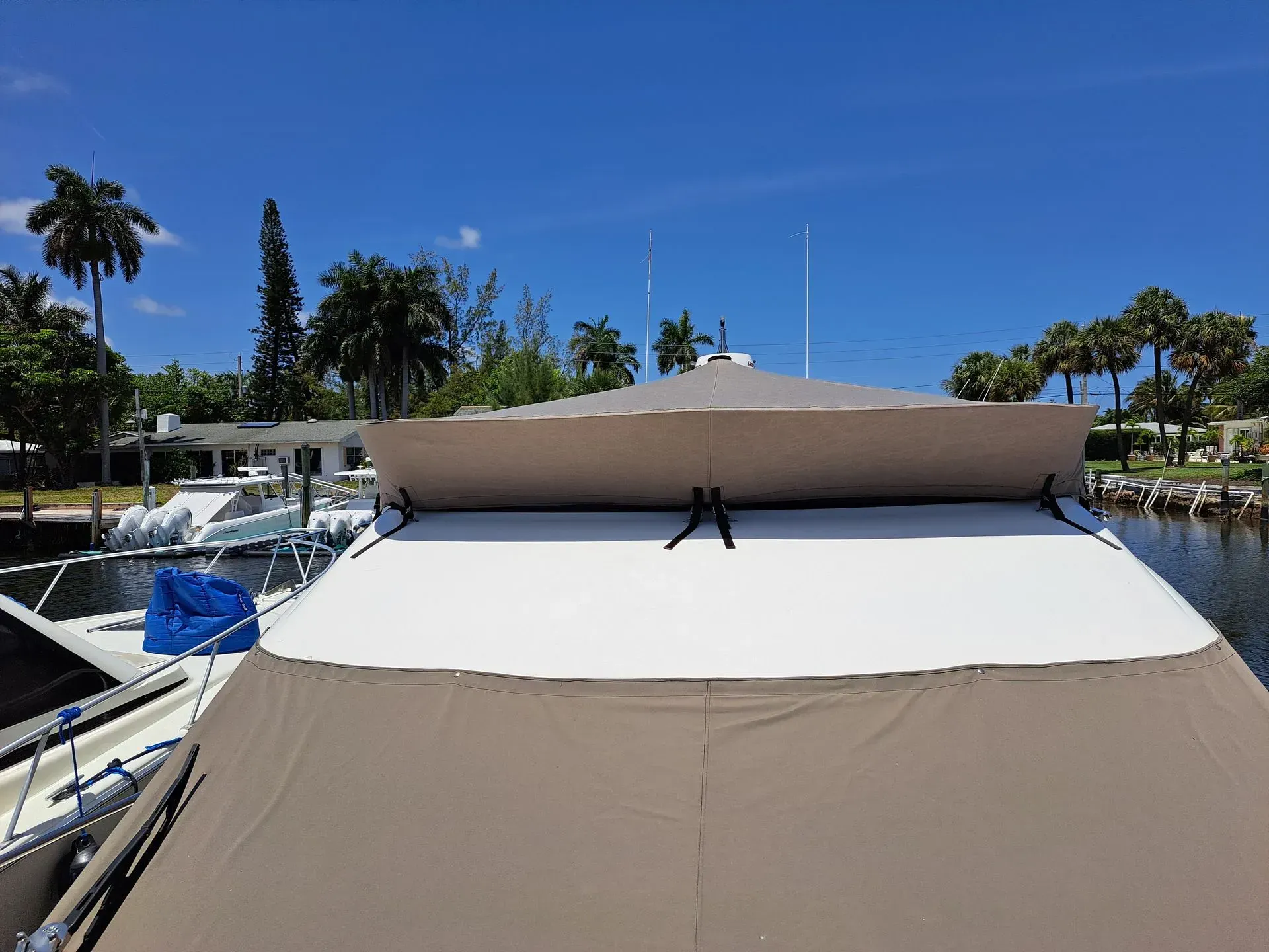 Tan and white boat deck with beige awning under a bright blue sky.