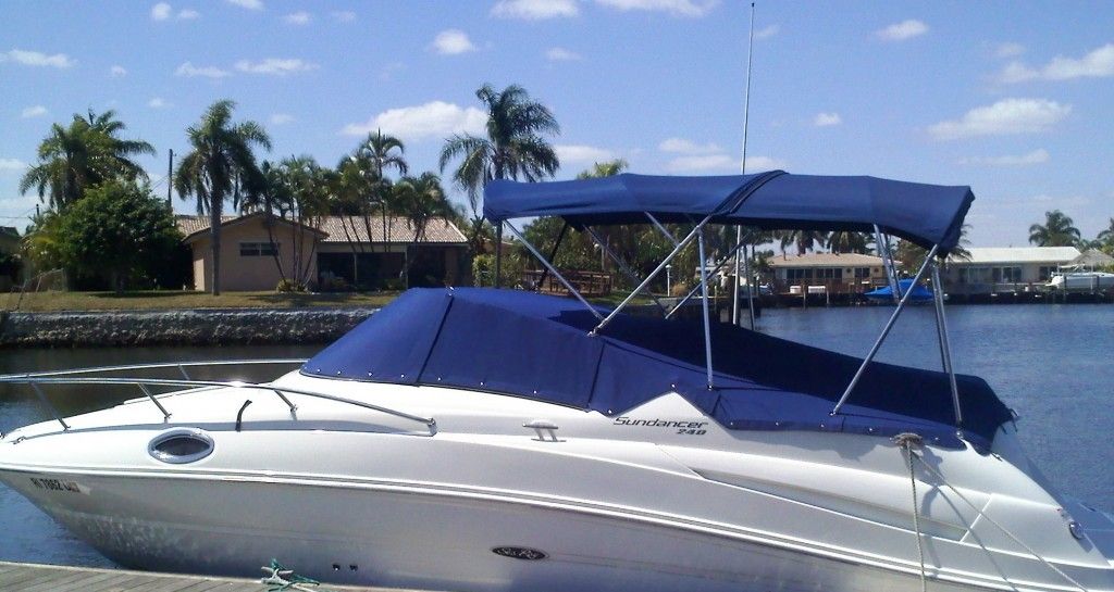 A white boat with a blue canopy is docked in the water
