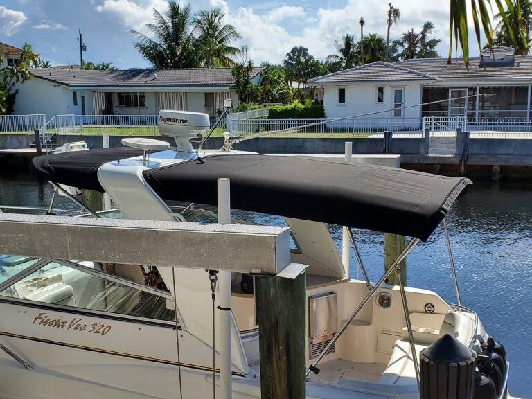 A boat with a black canopy is docked at a dock
