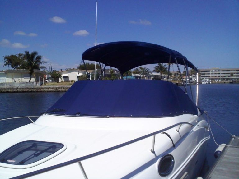 A white boat with a blue canopy is docked at a dock