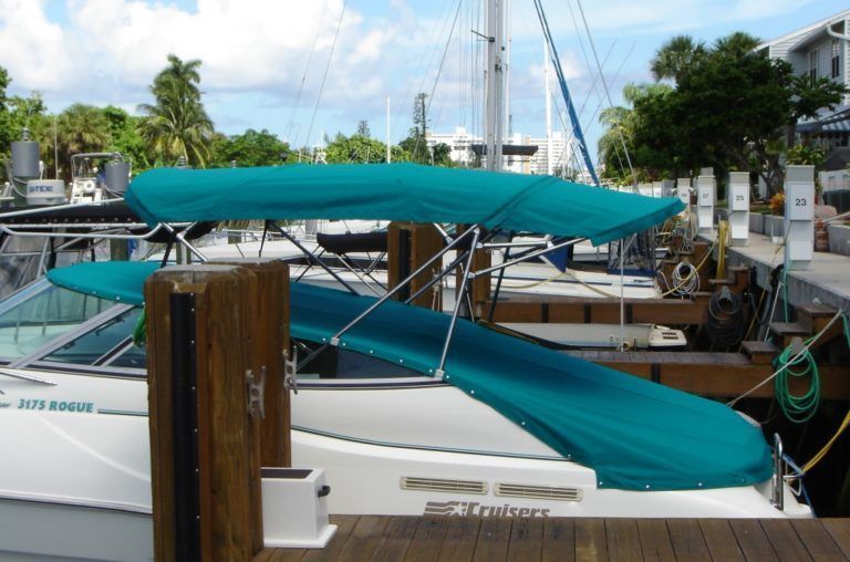 A boat with a green canopy is docked at a dock