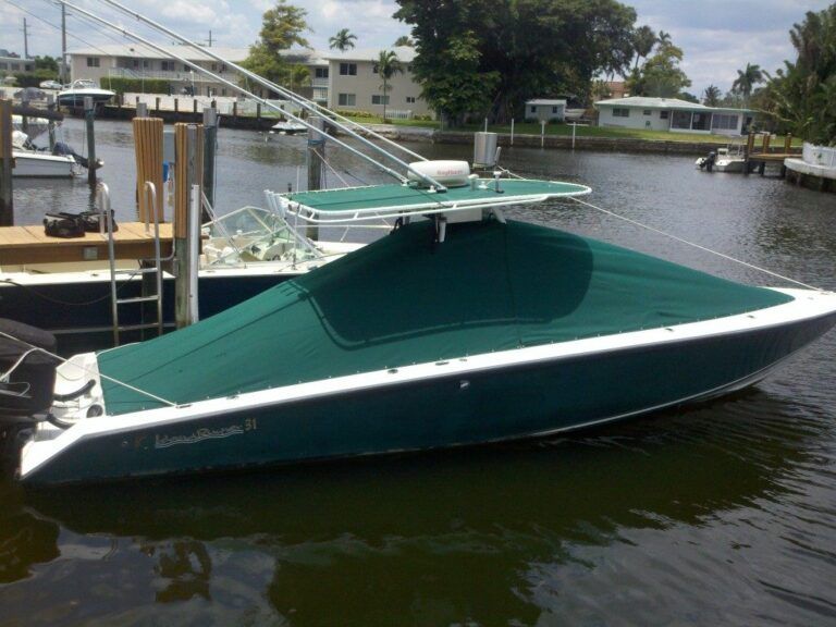 A boat with a green cover is docked in the water