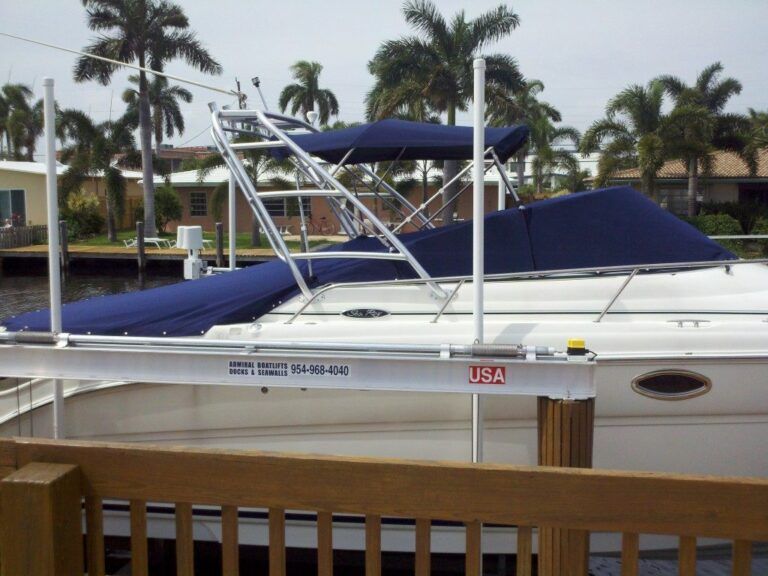 A white boat with a blue canopy is docked at a dock